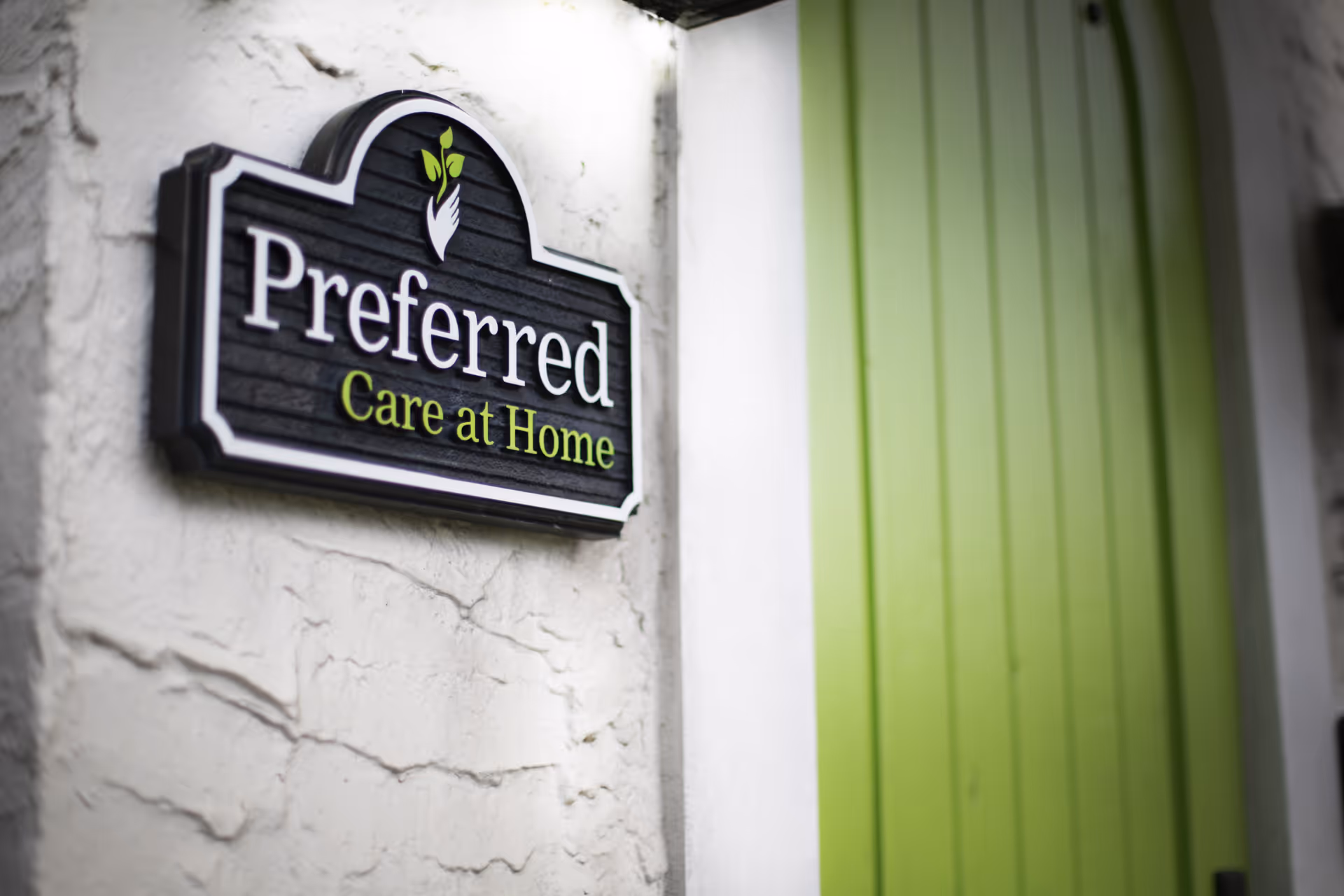Exterior wall sign reading 'Preferred Care at Home' beside a lime green door.