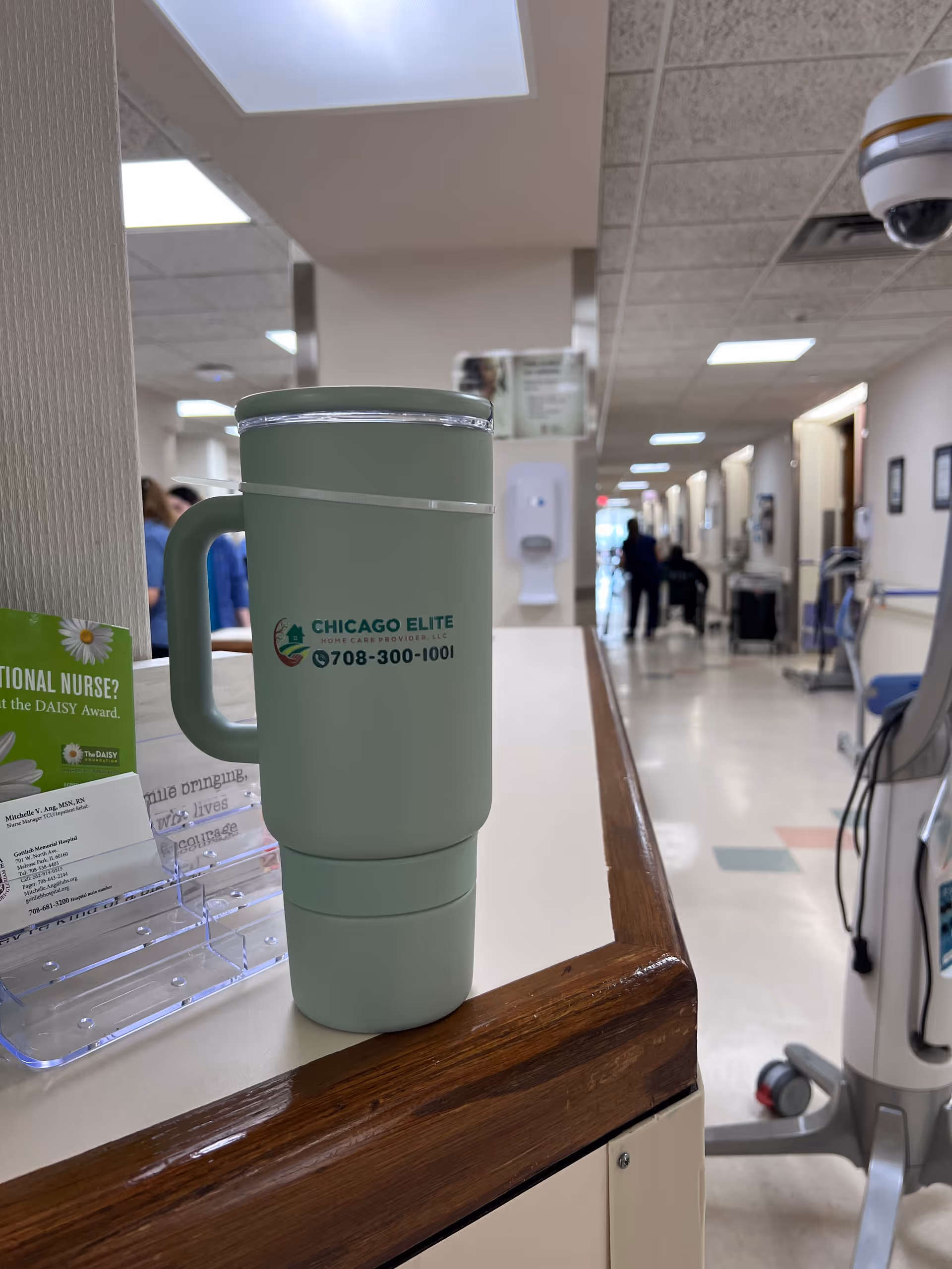 Mint tumbler with facility logo rests on a counter in a senior care corridor.