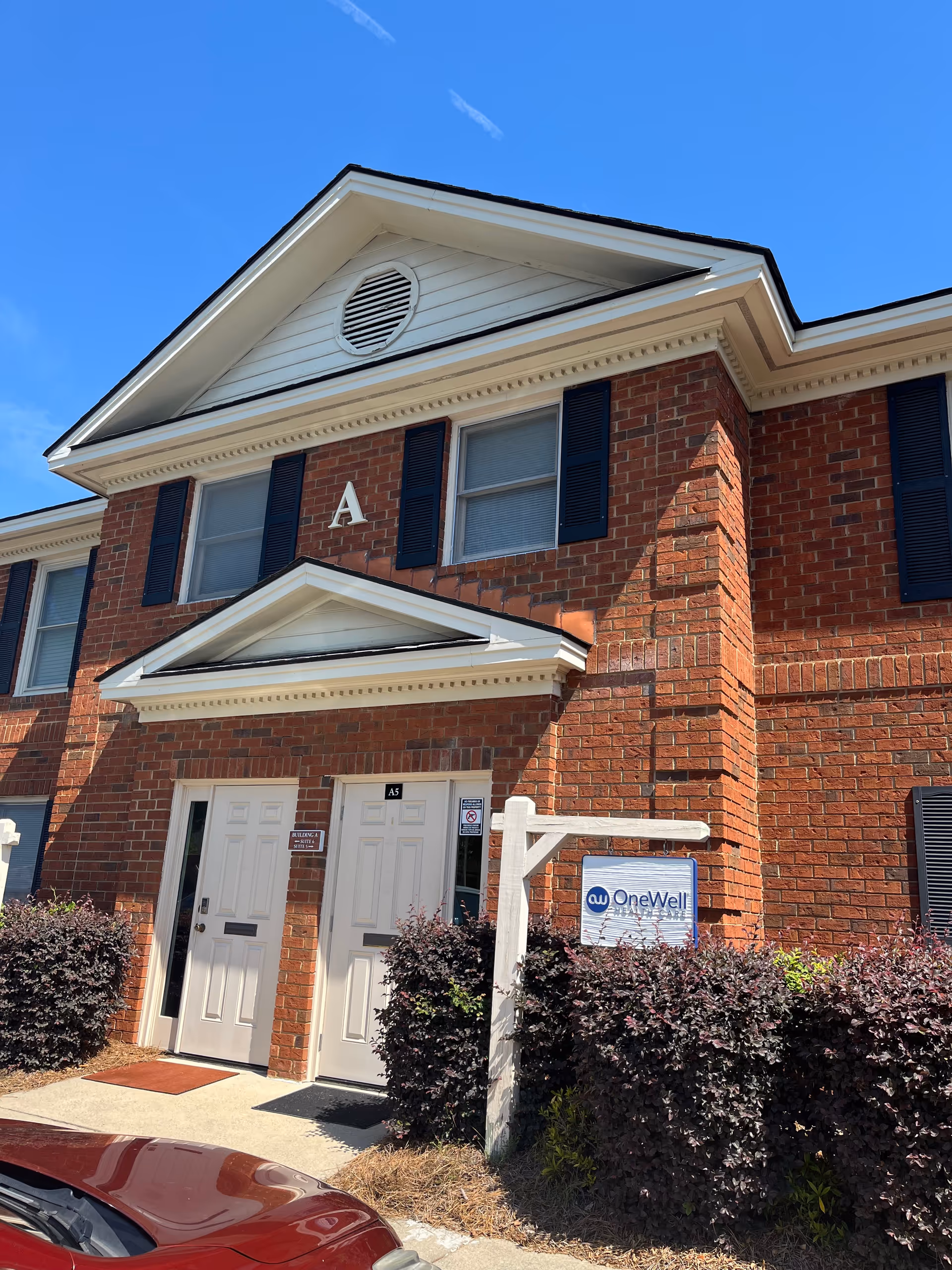 Brick building exterior with two white doors labeled A and a OneWell sign.