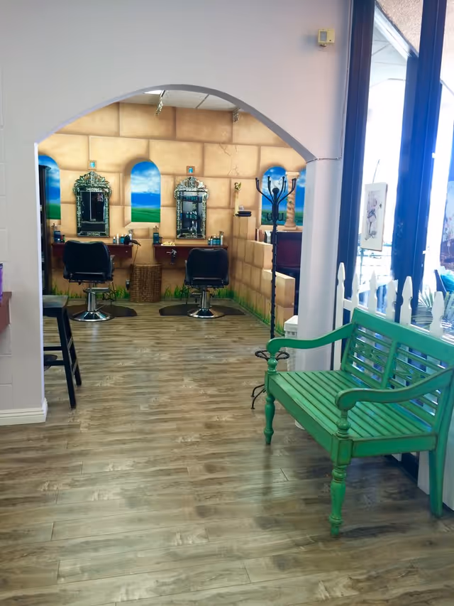Salon area inside facility with two styling chairs, mirrors, arch doorway, and a green bench.