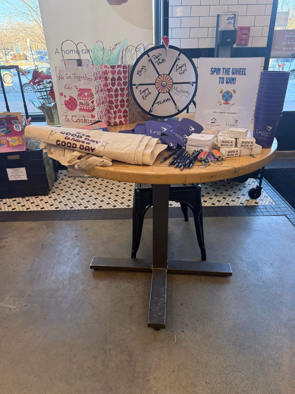 A promotional display table in a facility lobby with a prize wheel and gift bags.