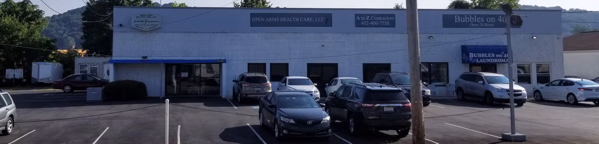 Front view of Open Arms Health Care, LLC building with parked cars in lot.