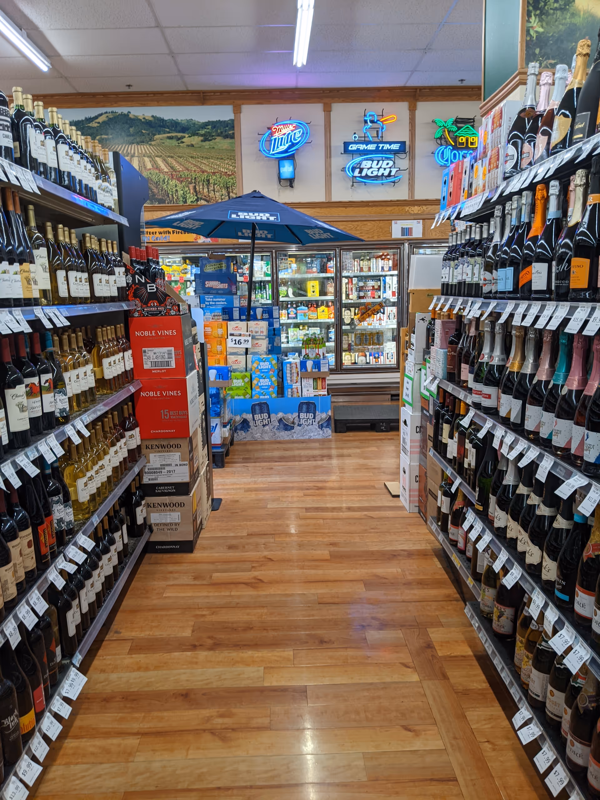 Wide aisle in Discount Drug Mart liquor section with numerous wine bottles on shelves