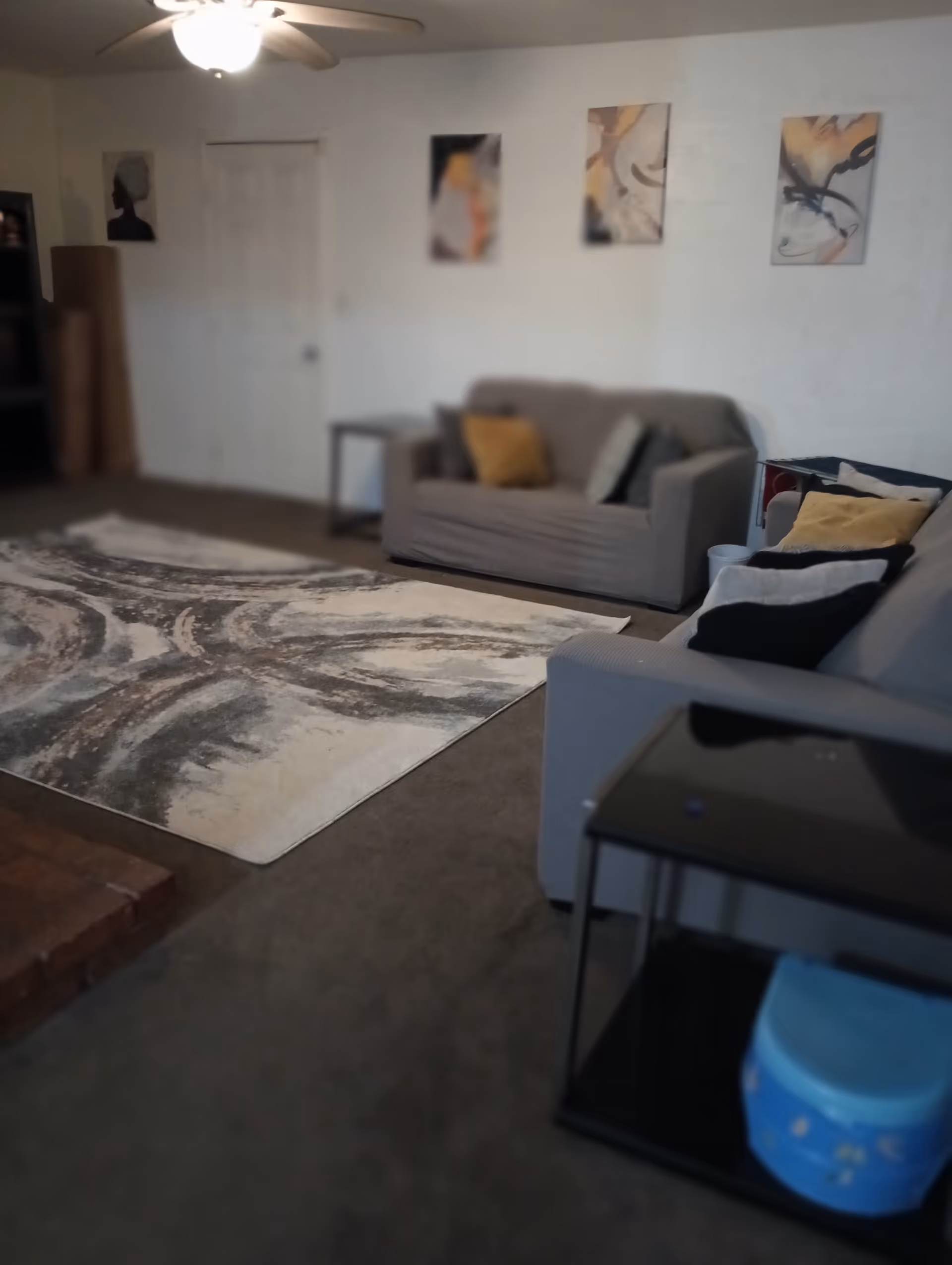 Cozy lounge area with gray sofas, abstract wall art, and a patterned rug.