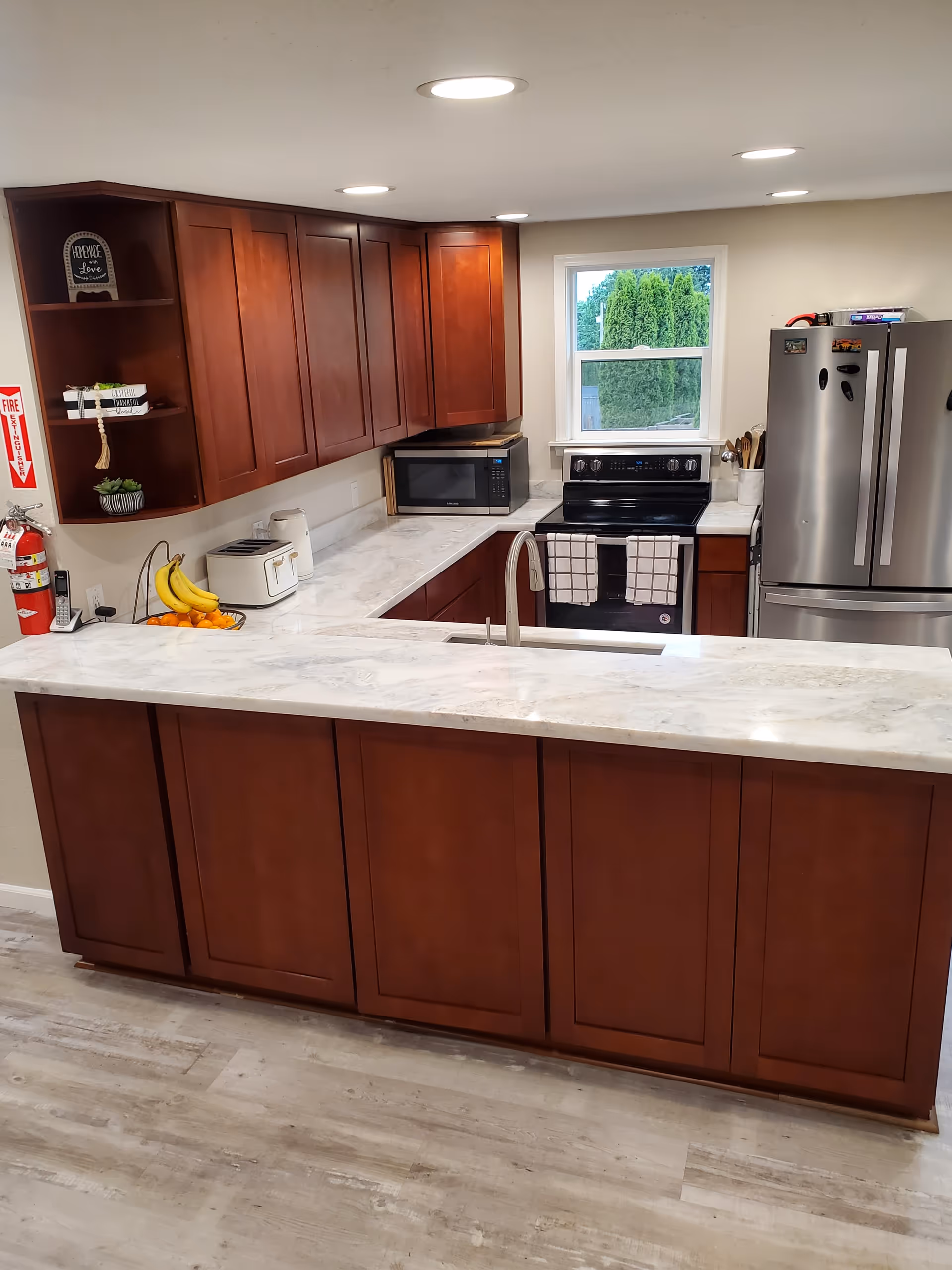 Modern kitchen with dark wood cabinets, marble countertops, and stainless appliances.