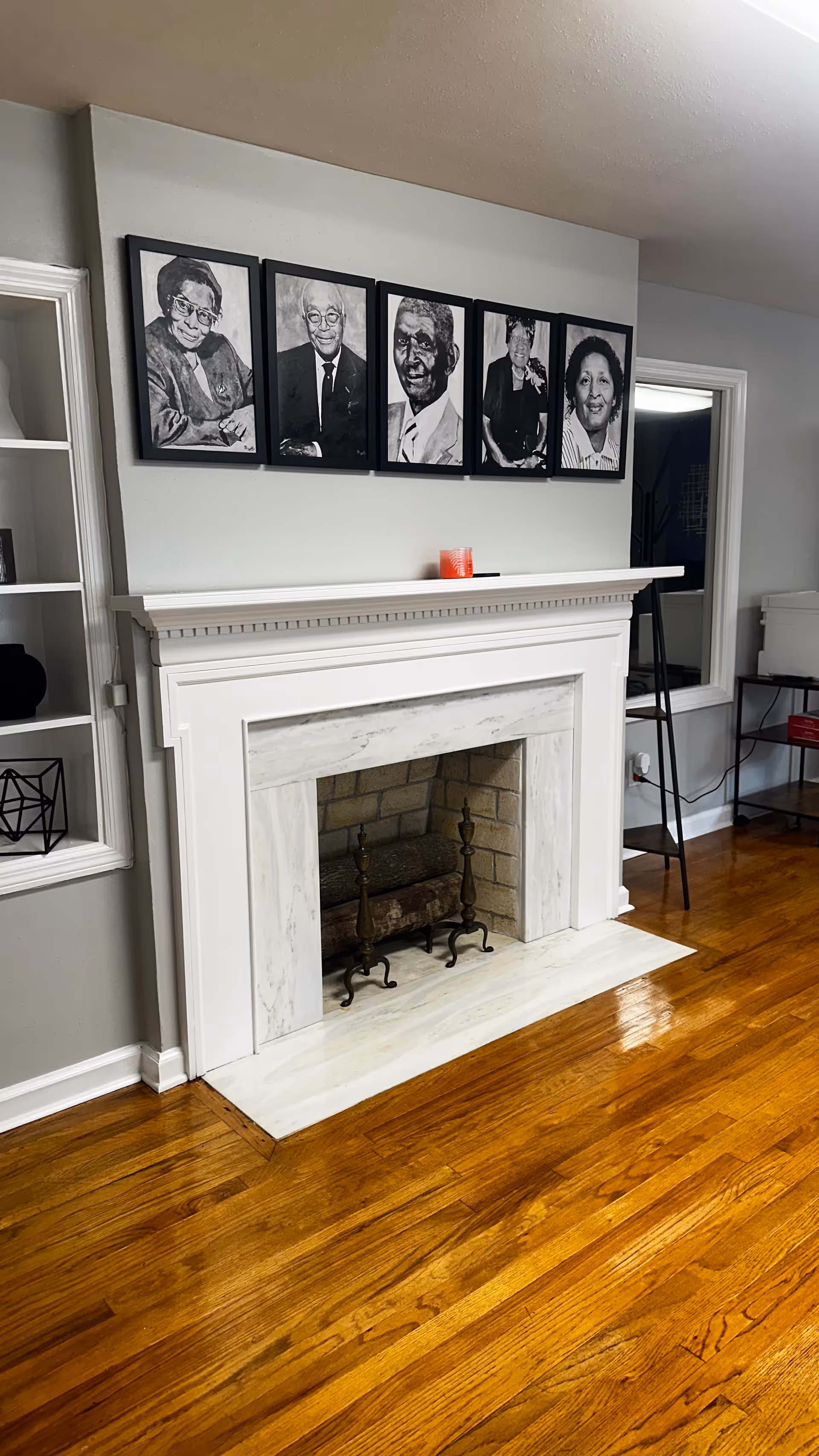 A bright living room with a white fireplace, portraits above, and a polished wooden floor.