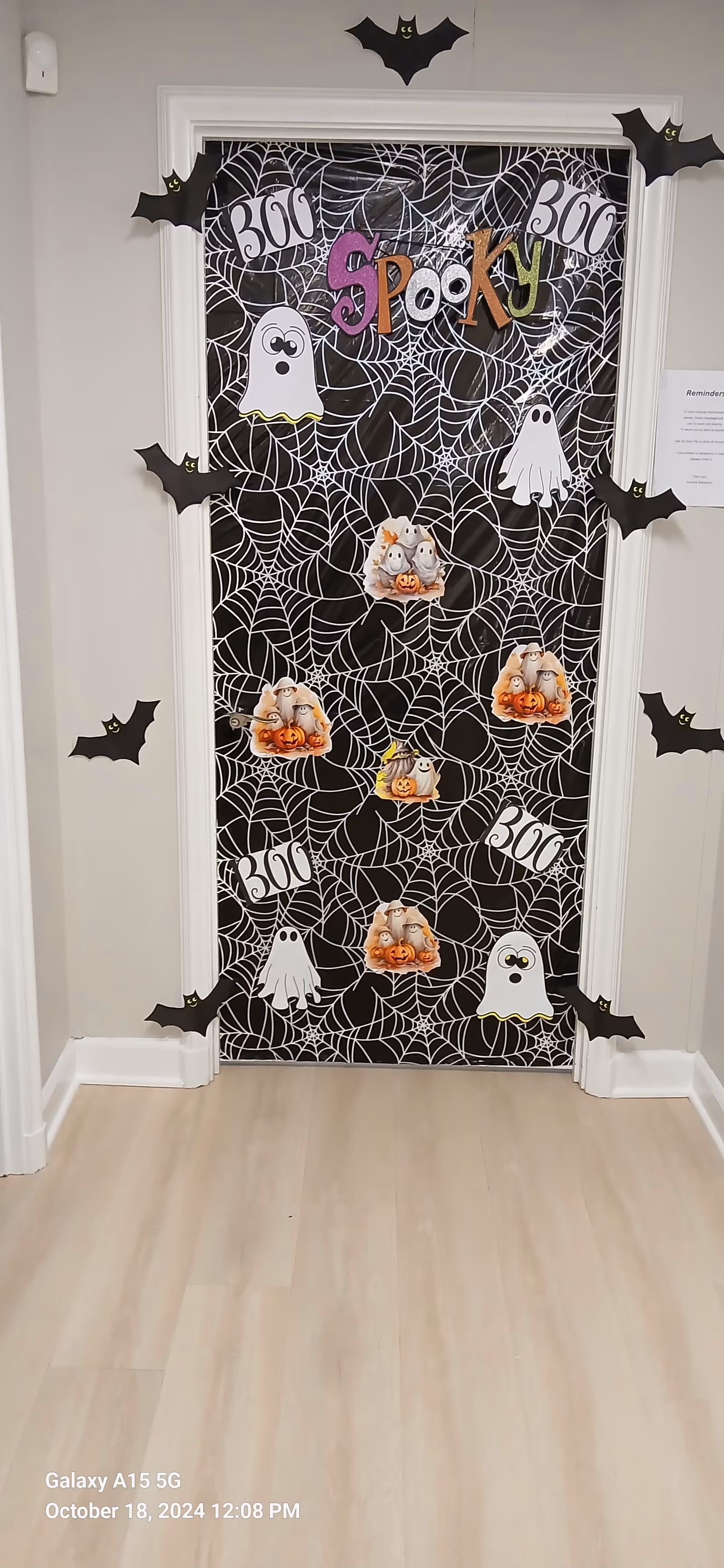 Decorated interior hallway doorway with spider webs, ghosts, pumpkins for Halloween.