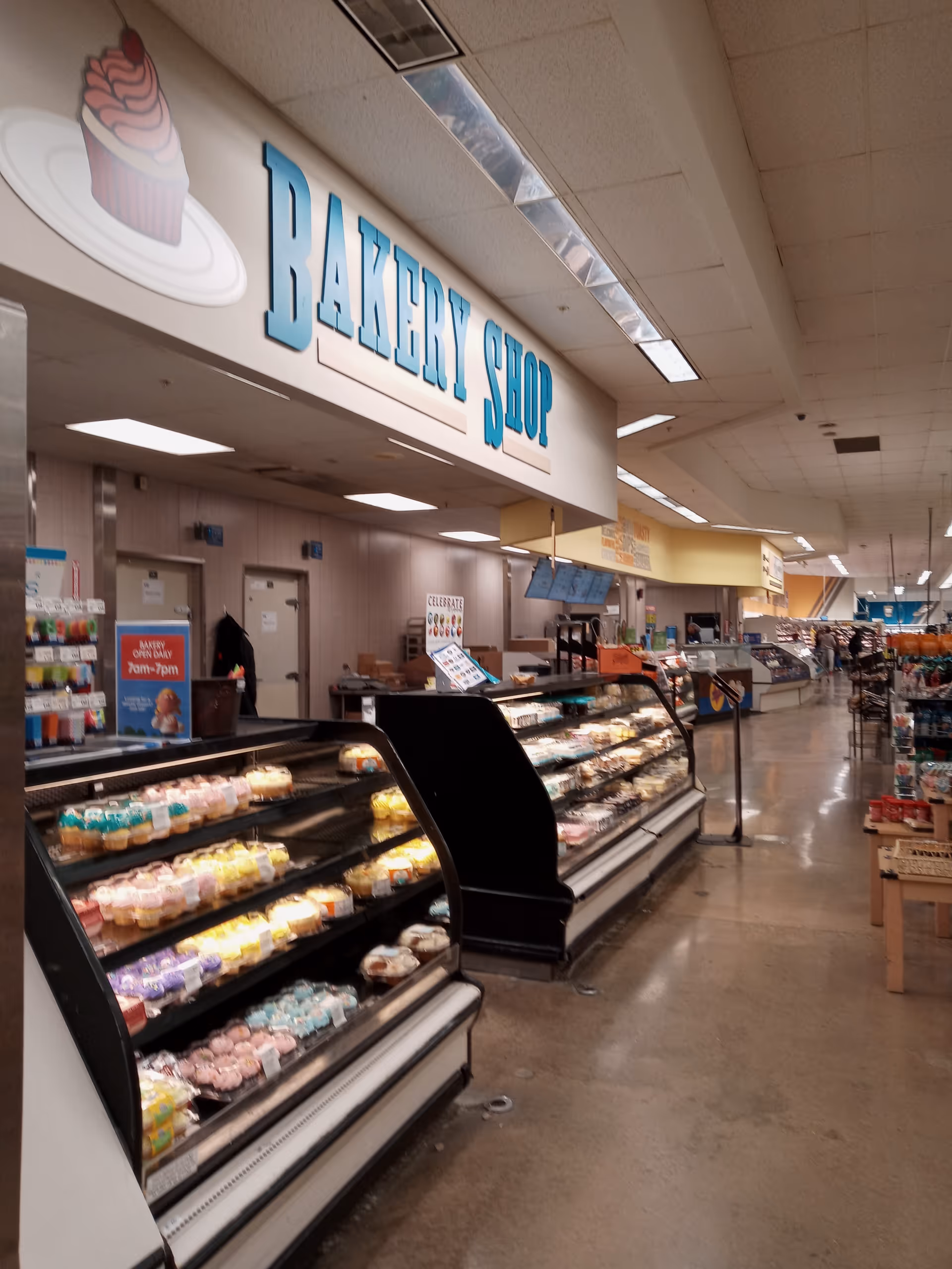 Inside a Kroger Pharmacy bakery shop with pastry displays along a wide aisle.