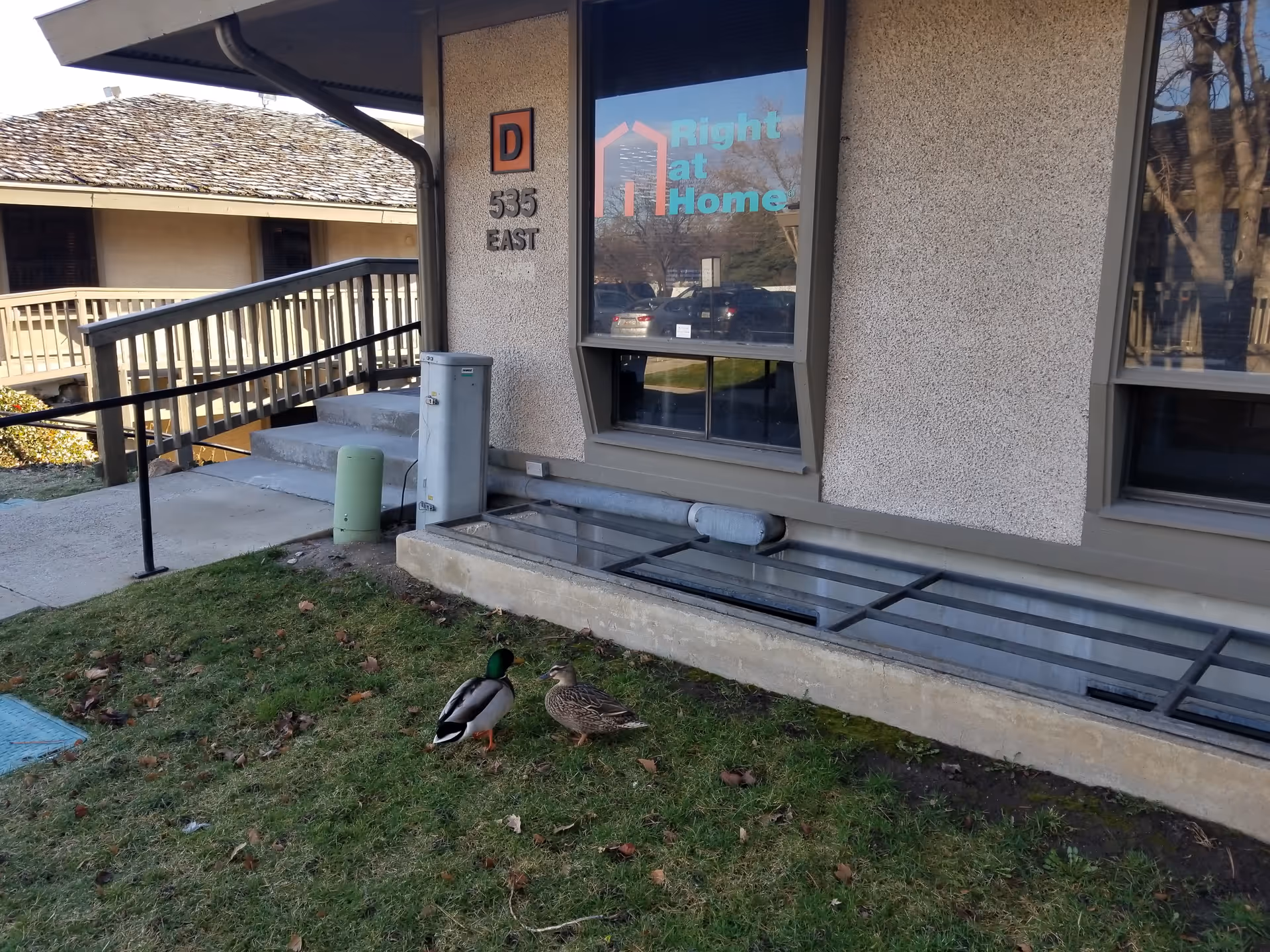 Exterior view of a Right at Home facility with stairs, railing, and a duck.