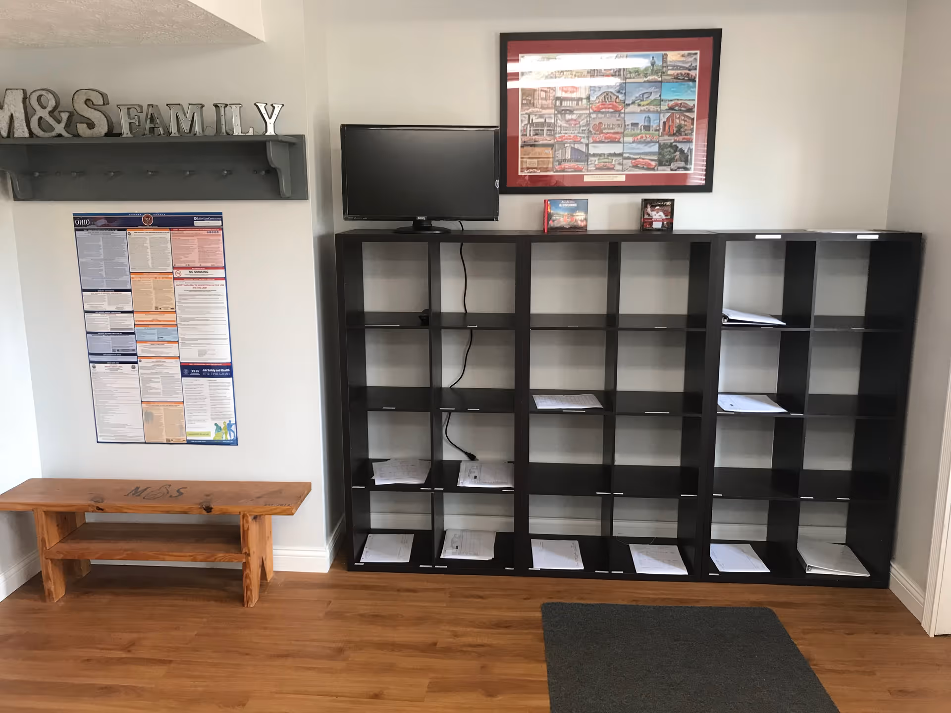 Reception area with M&S Family sign, black cubby shelves, a TV, and scattered papers.