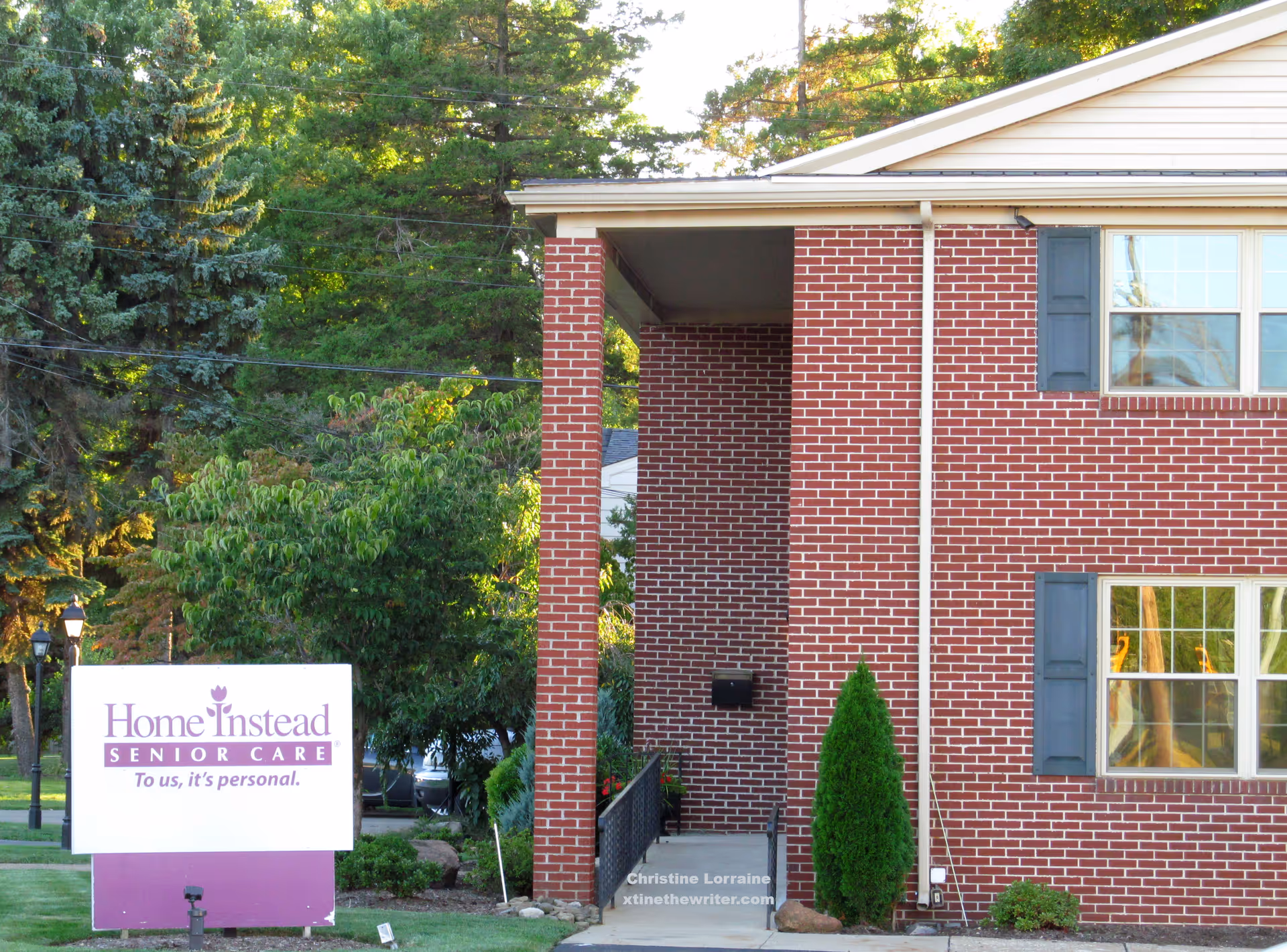 Brick exterior of Home Instead Senior Care building with entrance stairs and a sign.