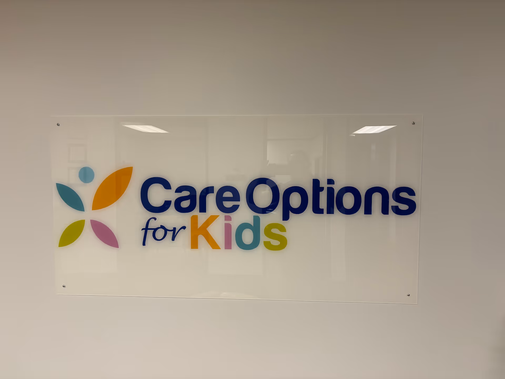 Interior wall sign reads Care Options for Kids with a colorful logo.