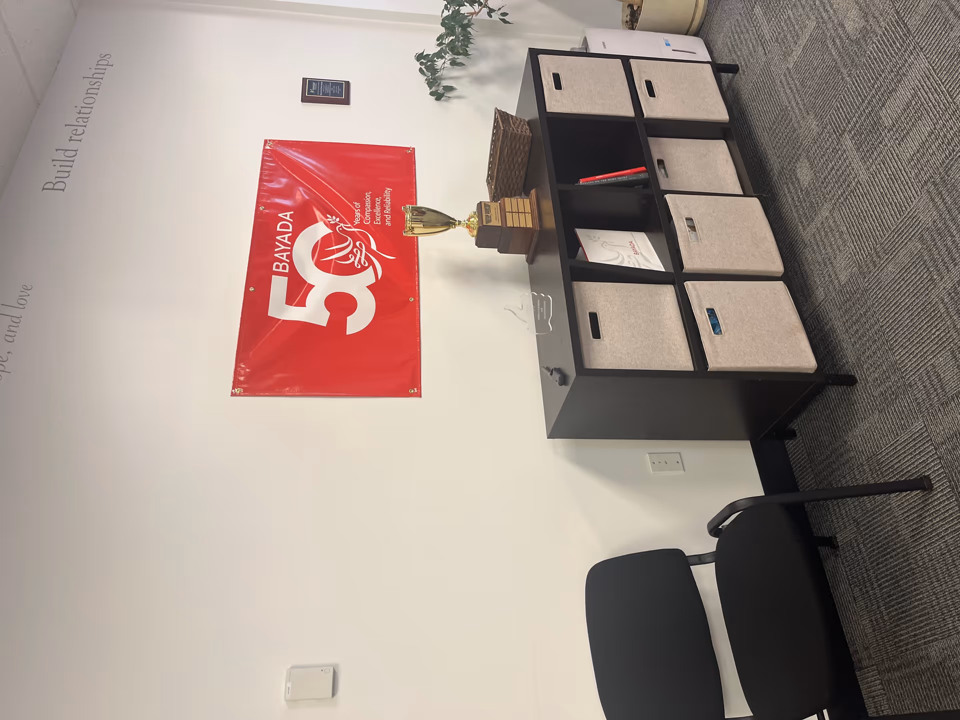Interior office area with BAYADA banner, desk, fabric cube storage, and chair.