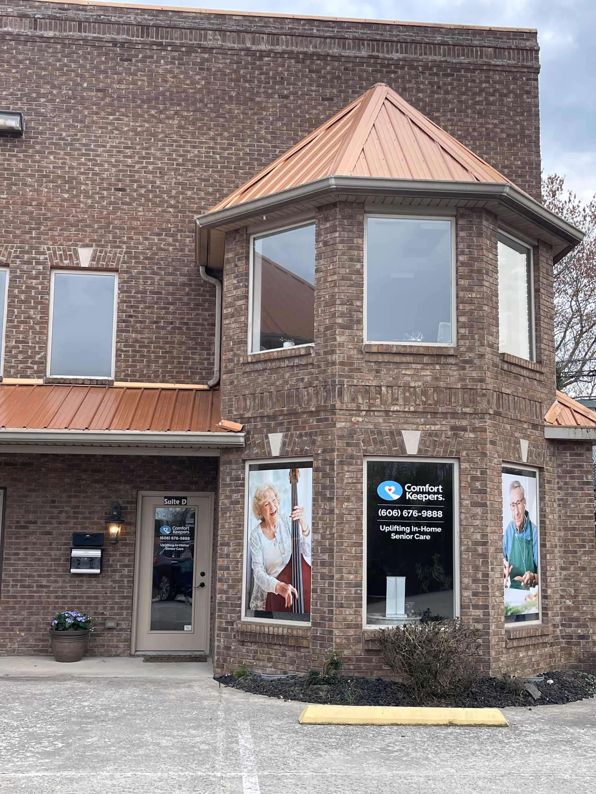 Brick exterior of Comfort Keepers building with large windows and posters