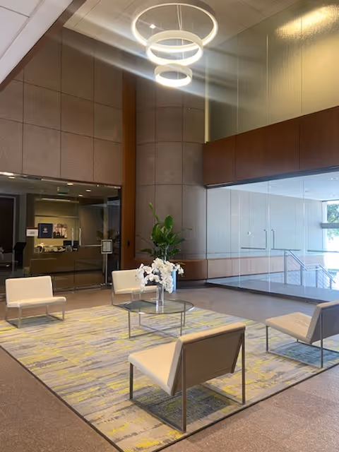 Modern senior living facility lobby with white chairs, glass coffee table, and a reception desk.
