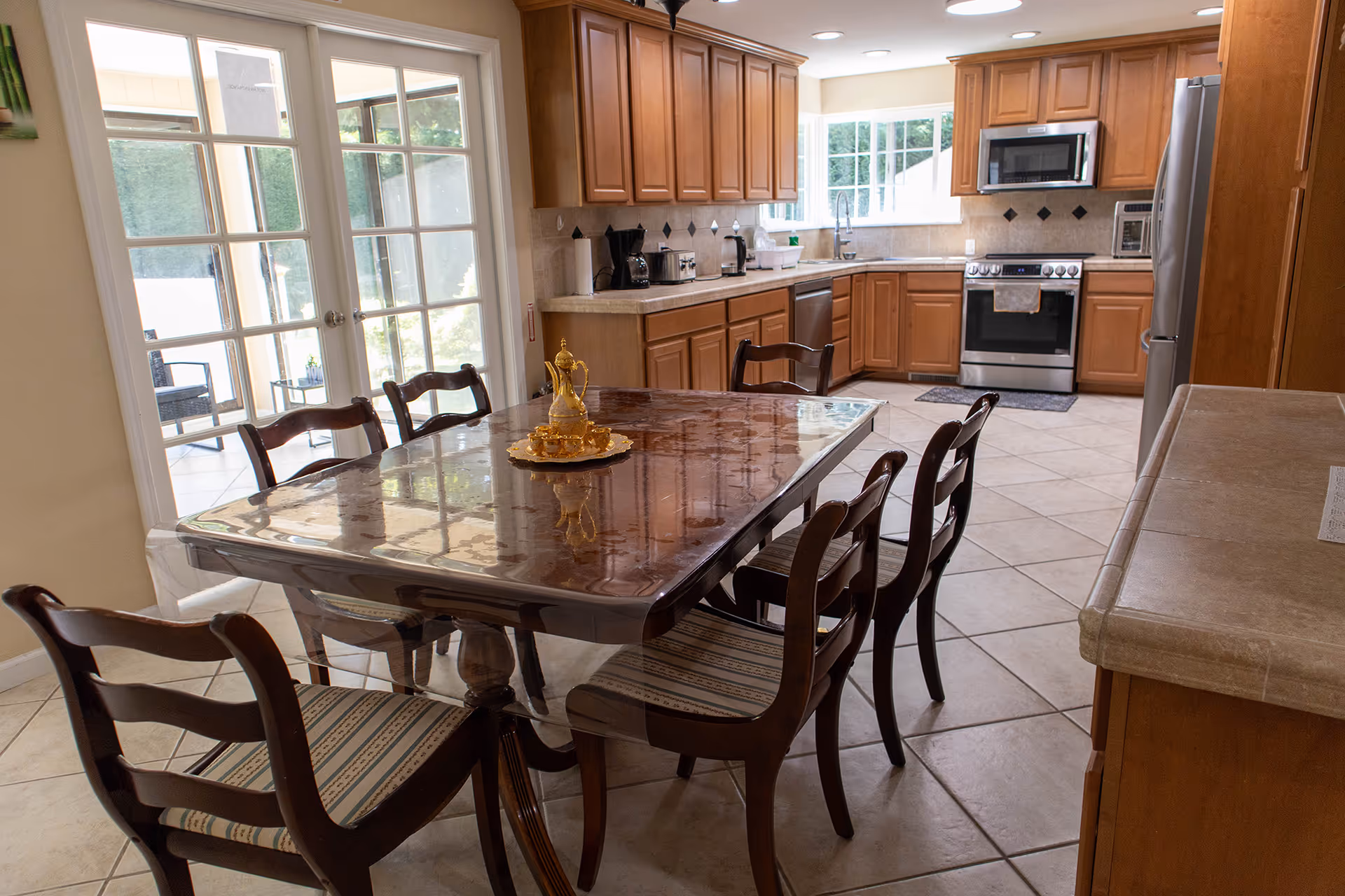 Open kitchen with wooden cabinets and a glass topped dining table surrounded by chairs