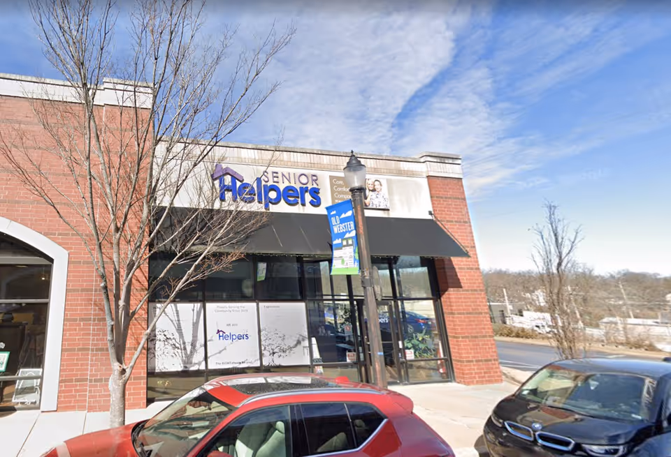 Exterior view of a Senior Helpers storefront with parked cars in front.