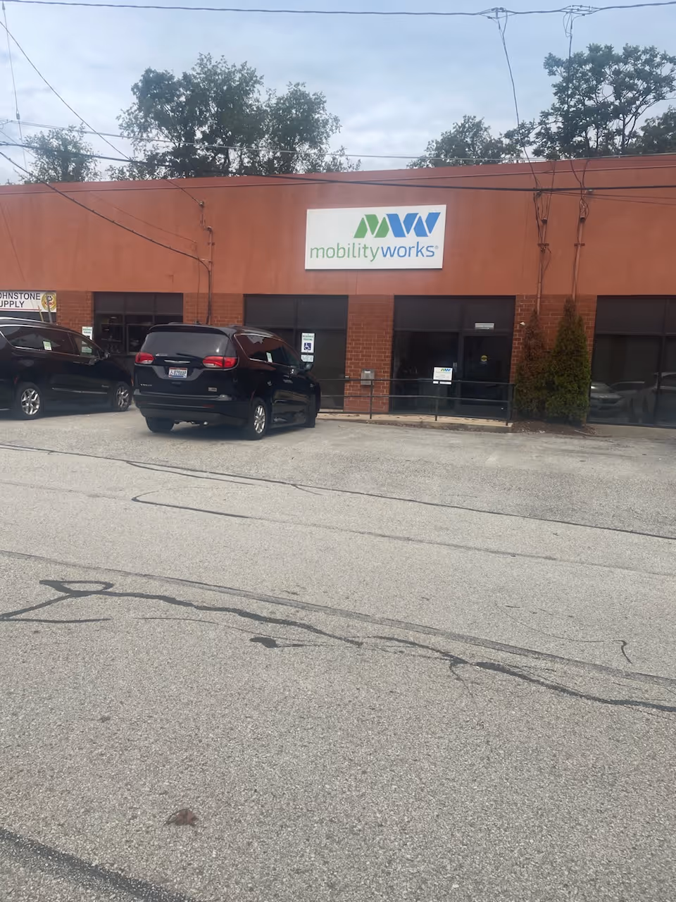 Exterior view of MobilityWorks building with a sign and parked cars.