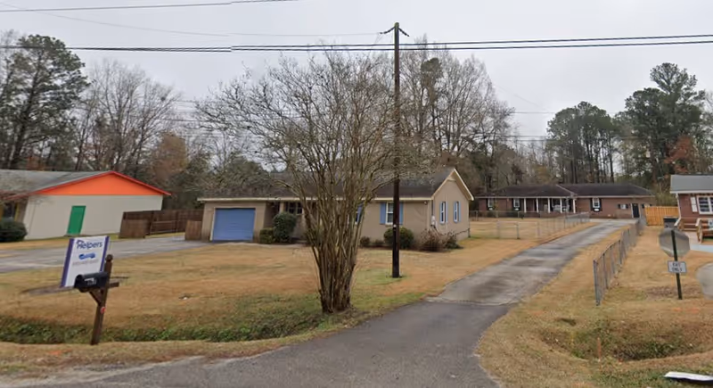 Exterior view of a Senior Helpers facility with curved driveway and yard.
