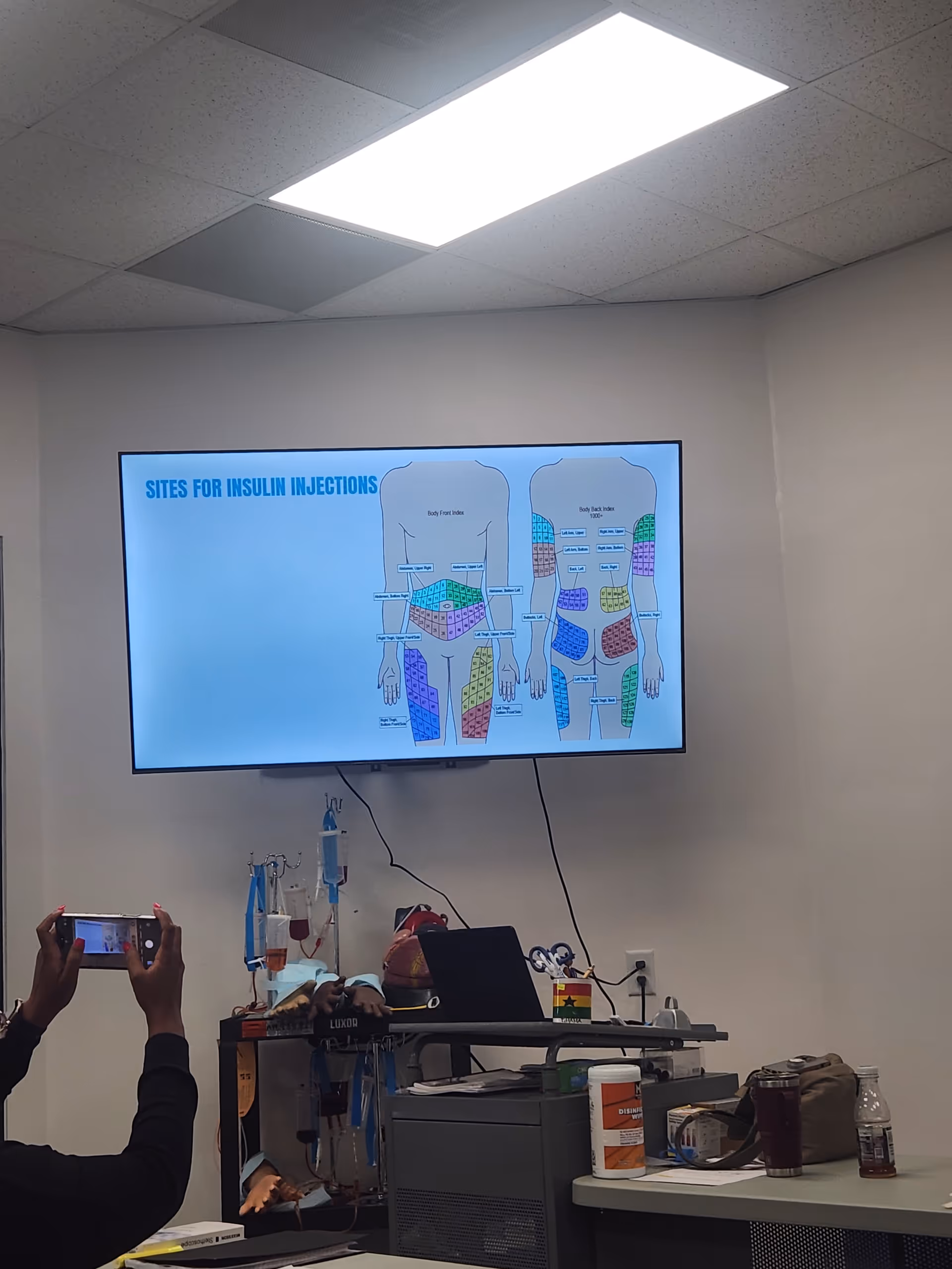 Training room with a large screen displaying insulin injection sites and medical equipment.