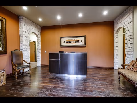 Reception lobby with curved dark wood desk, stone accents, and lounge chairs.
