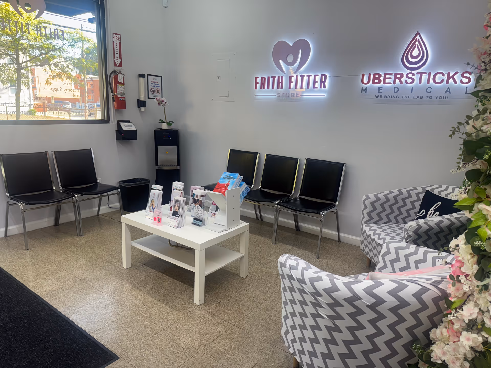 Reception and waiting area with black chairs, a white coffee table, brochures, and neon signage.
