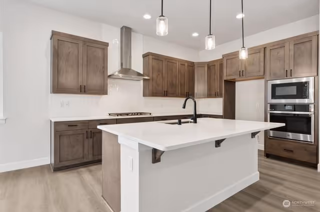 Bright modern kitchen with island, wooden cabinets, and stainless steel appliances.