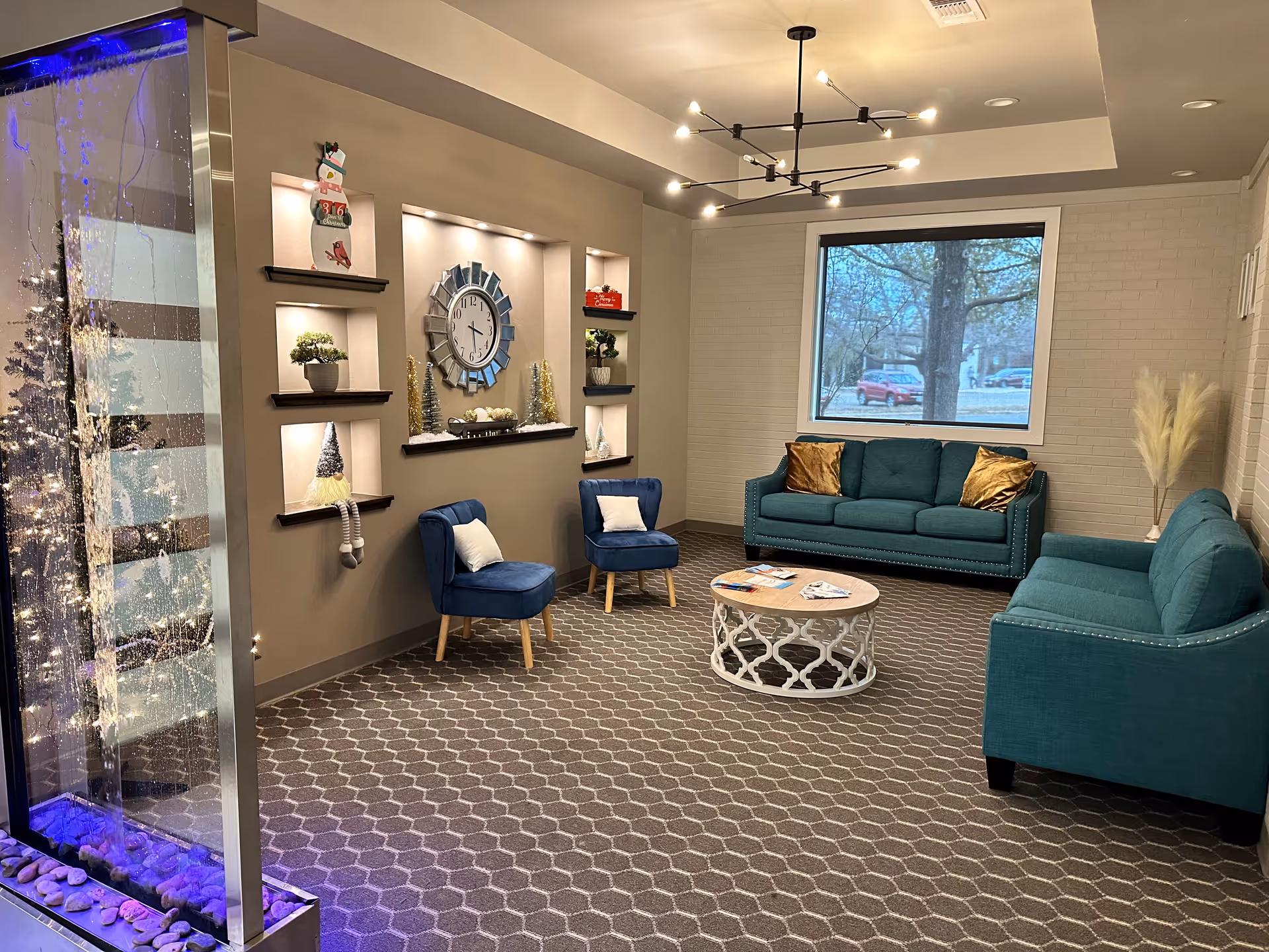 Indoor lounge area with teal sofas, blue chairs, coffee table, and wall clock decor