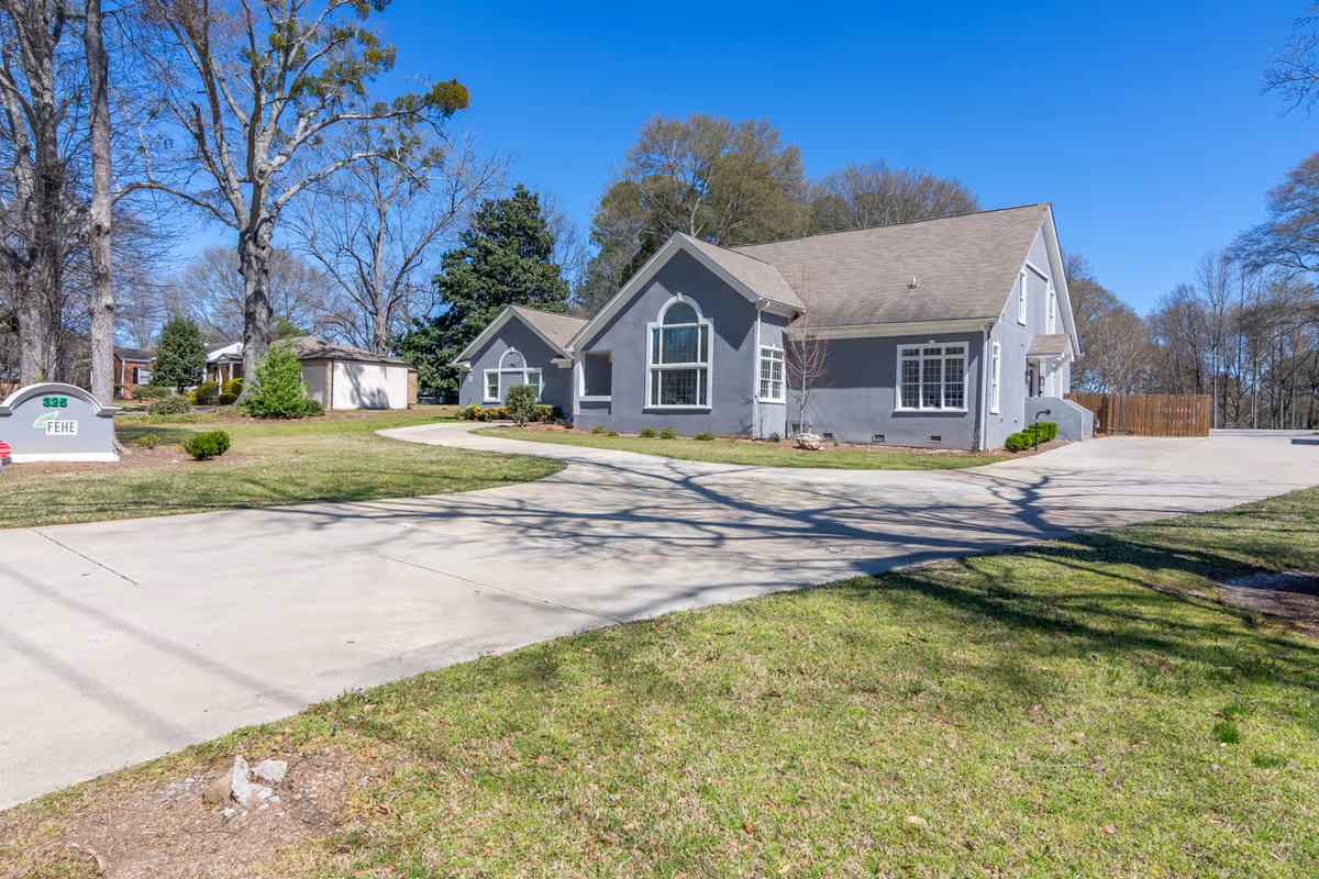 Grey single-story Fehe Private Healthcare Services building with curved driveway and lawn.