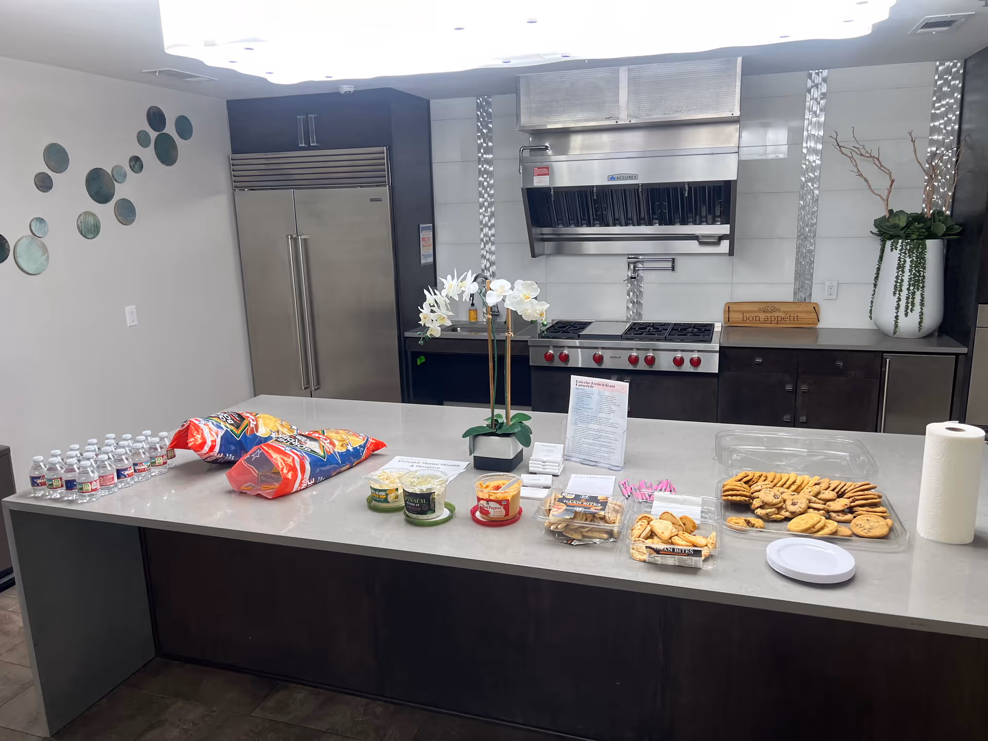 Modern kitchen island with snacks, water bottles, cookies, and stainless appliances.