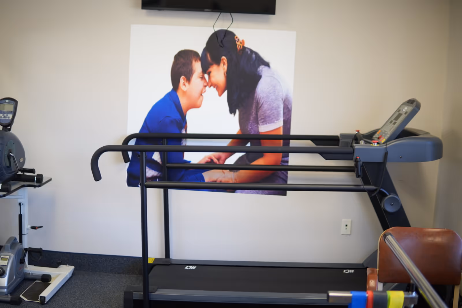 Senior fitness room with a treadmill and cardio equipment, large wall poster in background