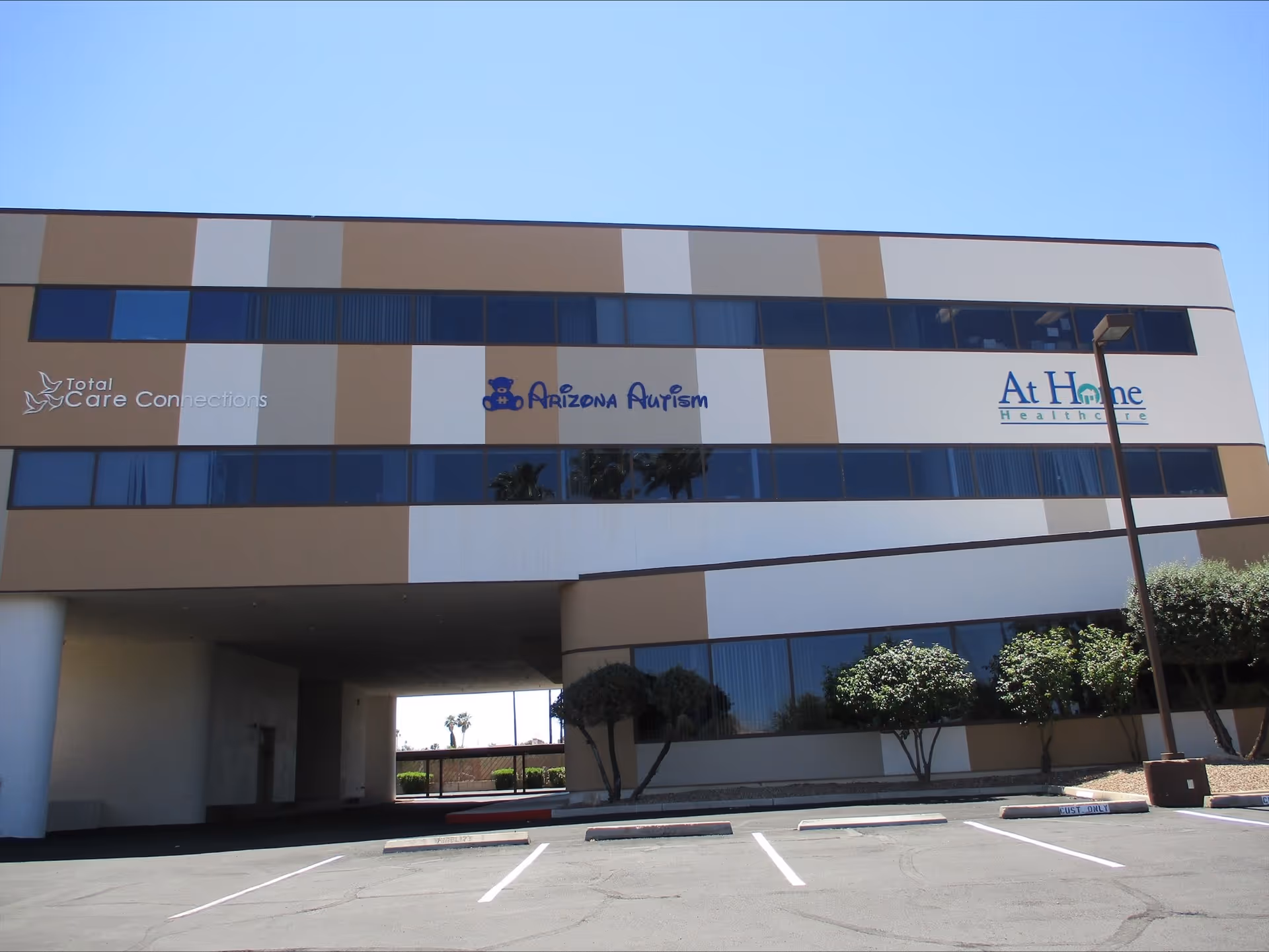 Exterior of a modern two-story building with Arizona Autism signage and parking.