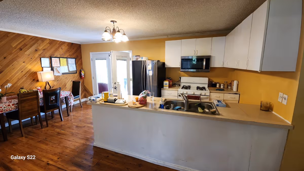 Open kitchen and dining area with white cabinets, yellow walls, and hardwood floors.