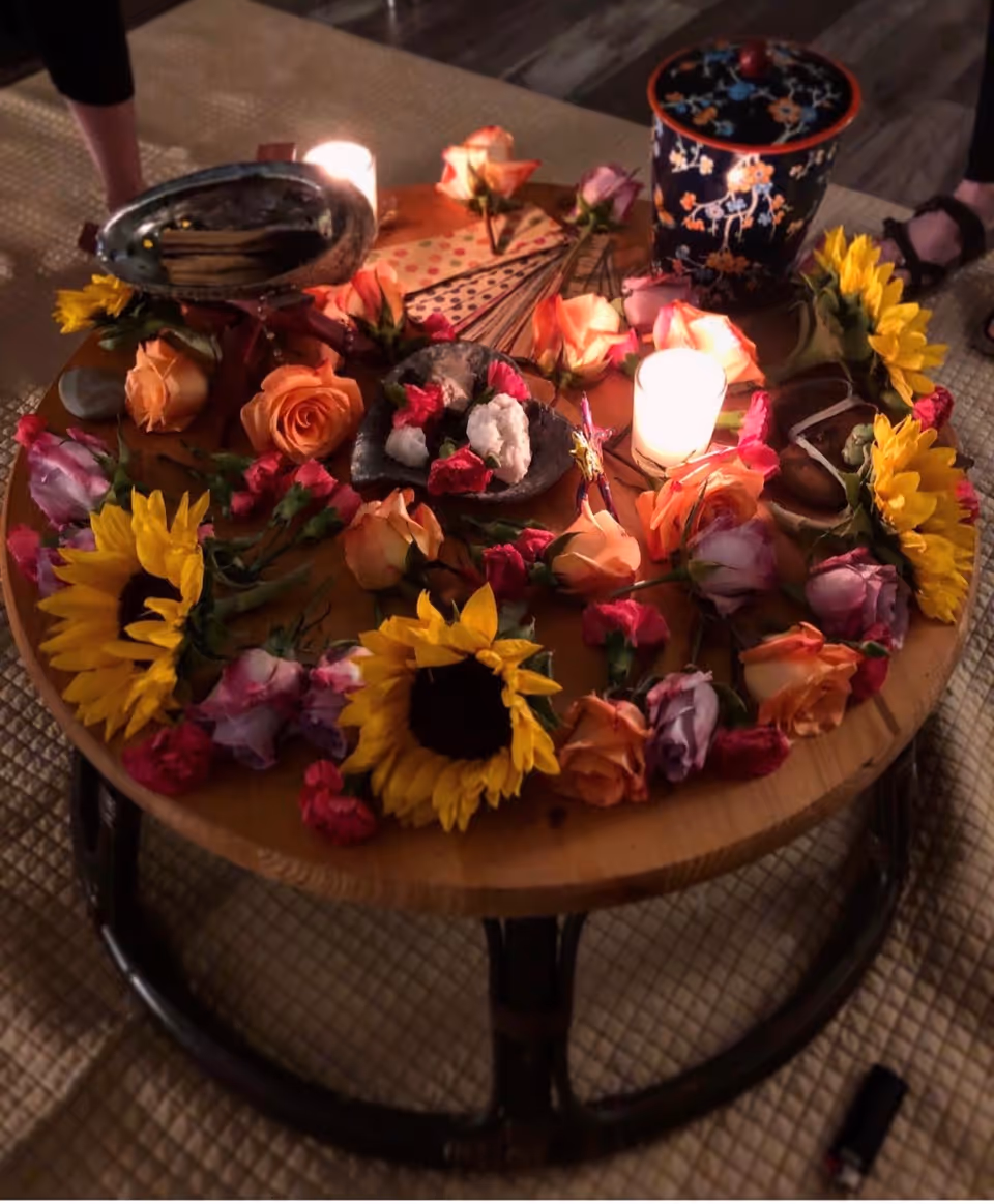 Round wooden table with sunflowers, roses, candles, and decorative items indoors.