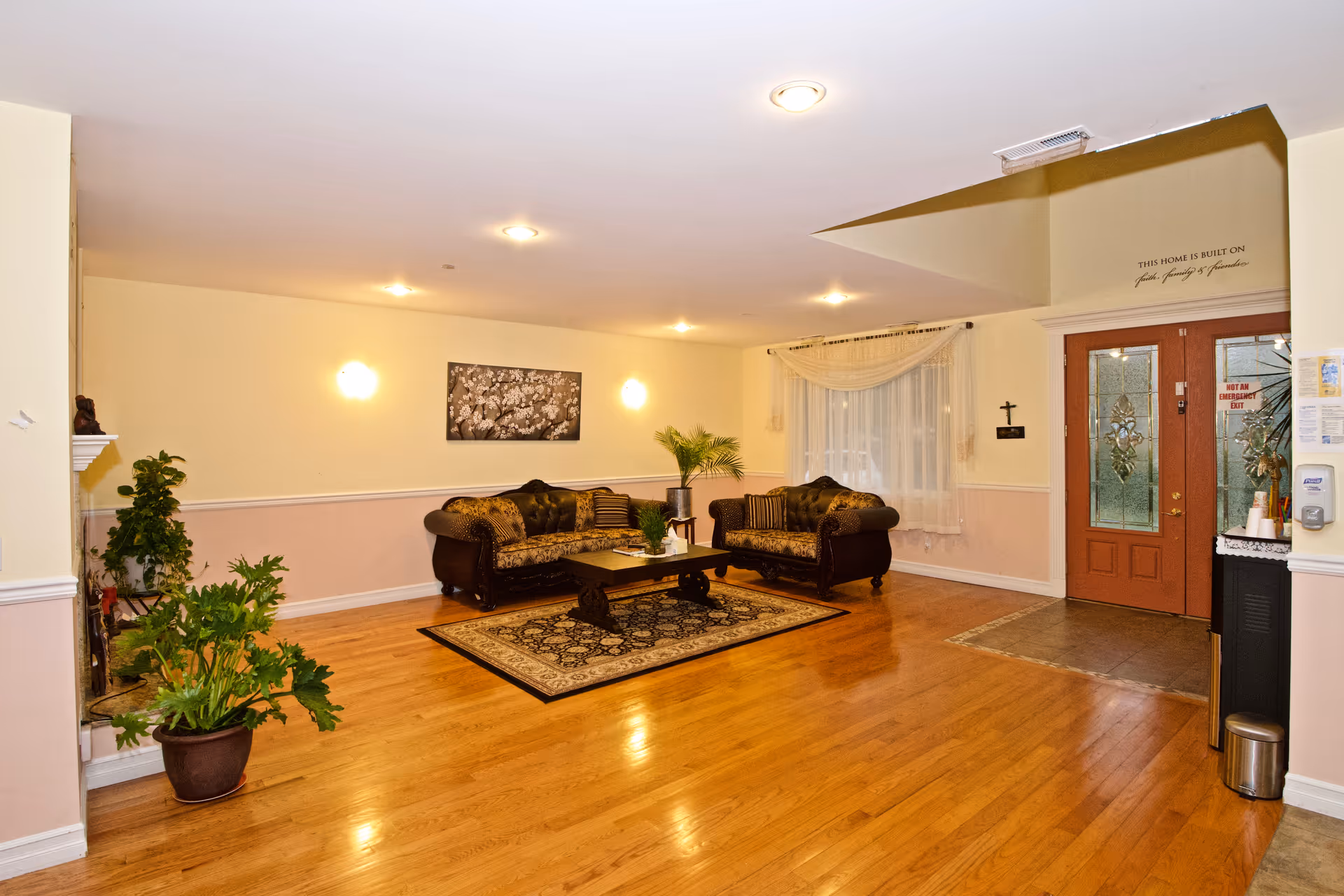 Spacious lobby with brown sofas, coffee table, plants, and an entry door.