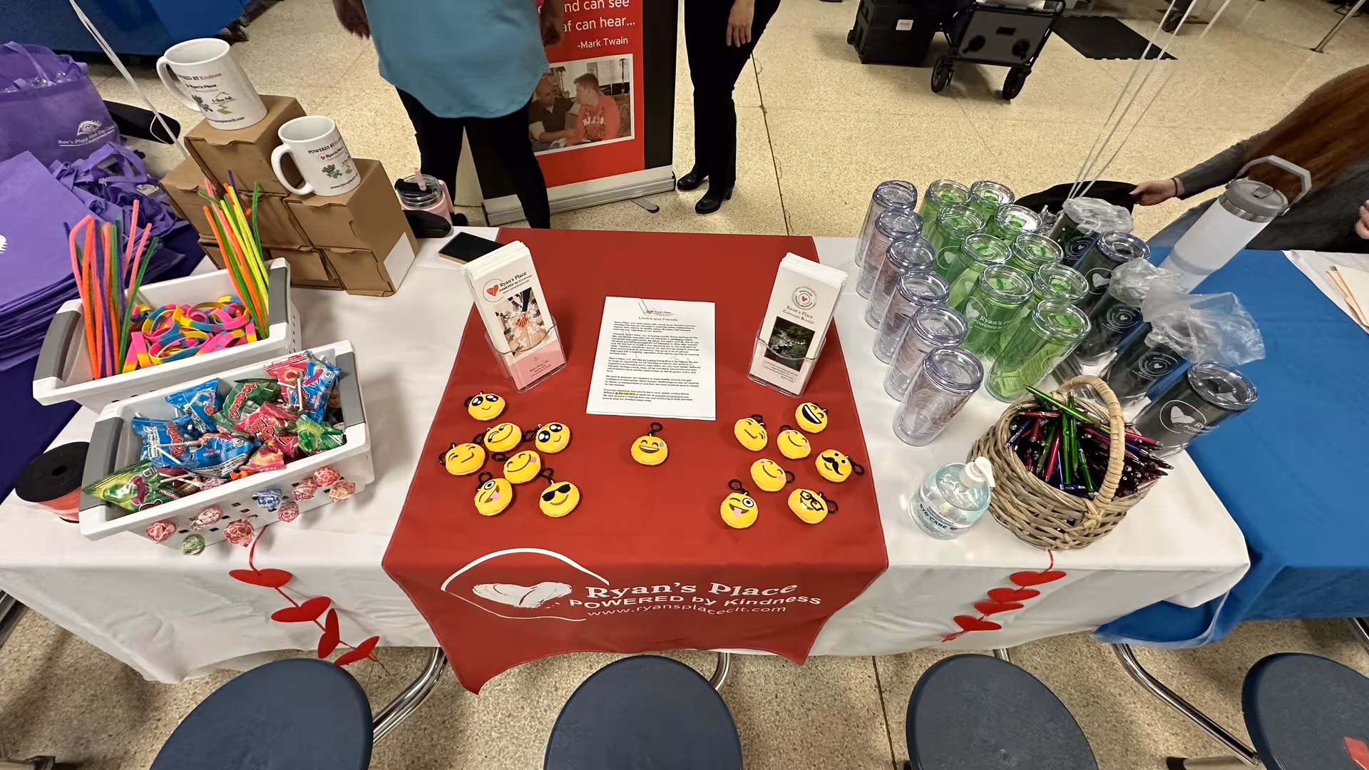 Indoor event table with candies, magnets, cups, and branded materials for Ryan's Place