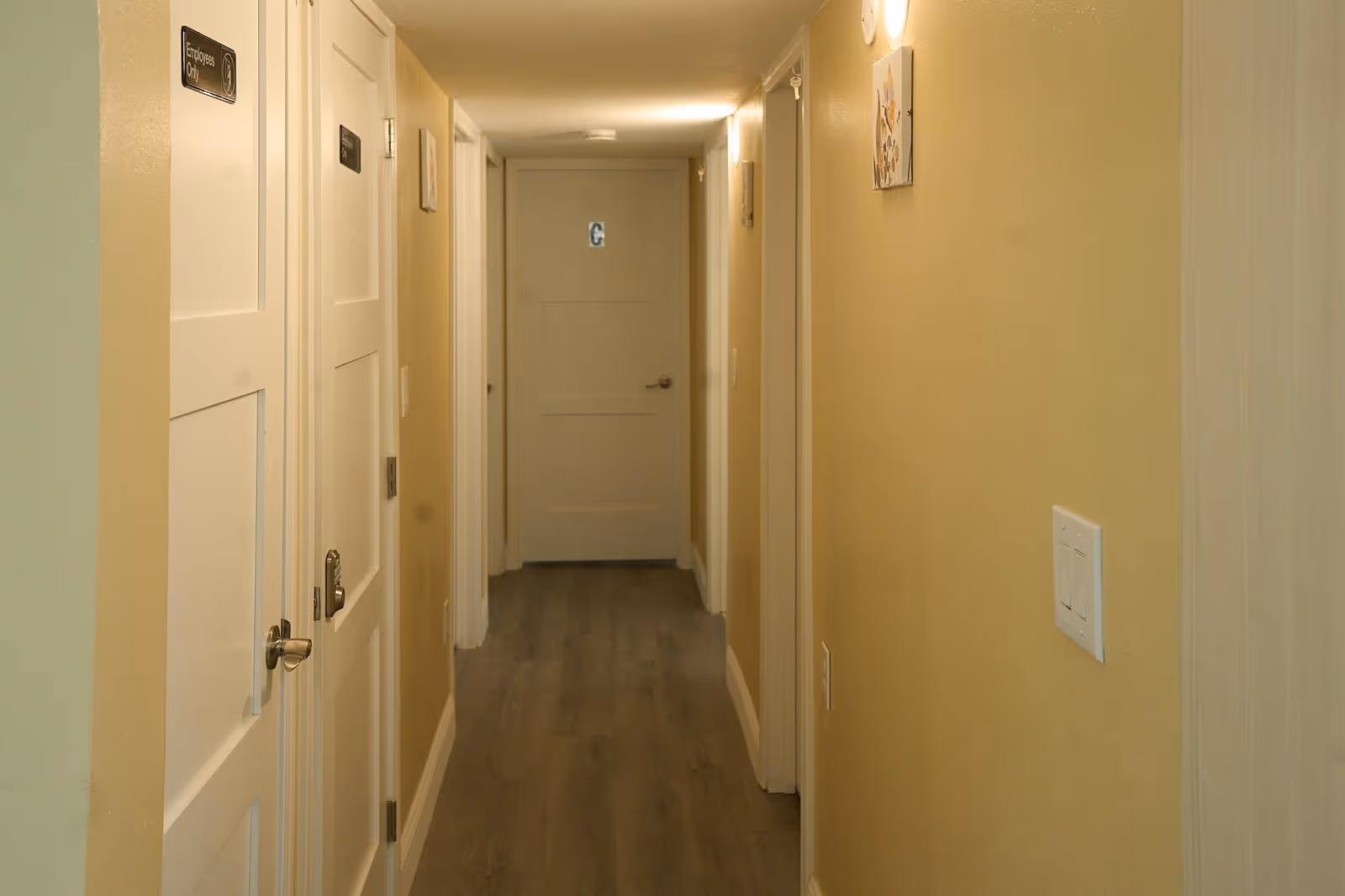 Long beige hallway in Apex Care Adult Family Home with doors along both walls.