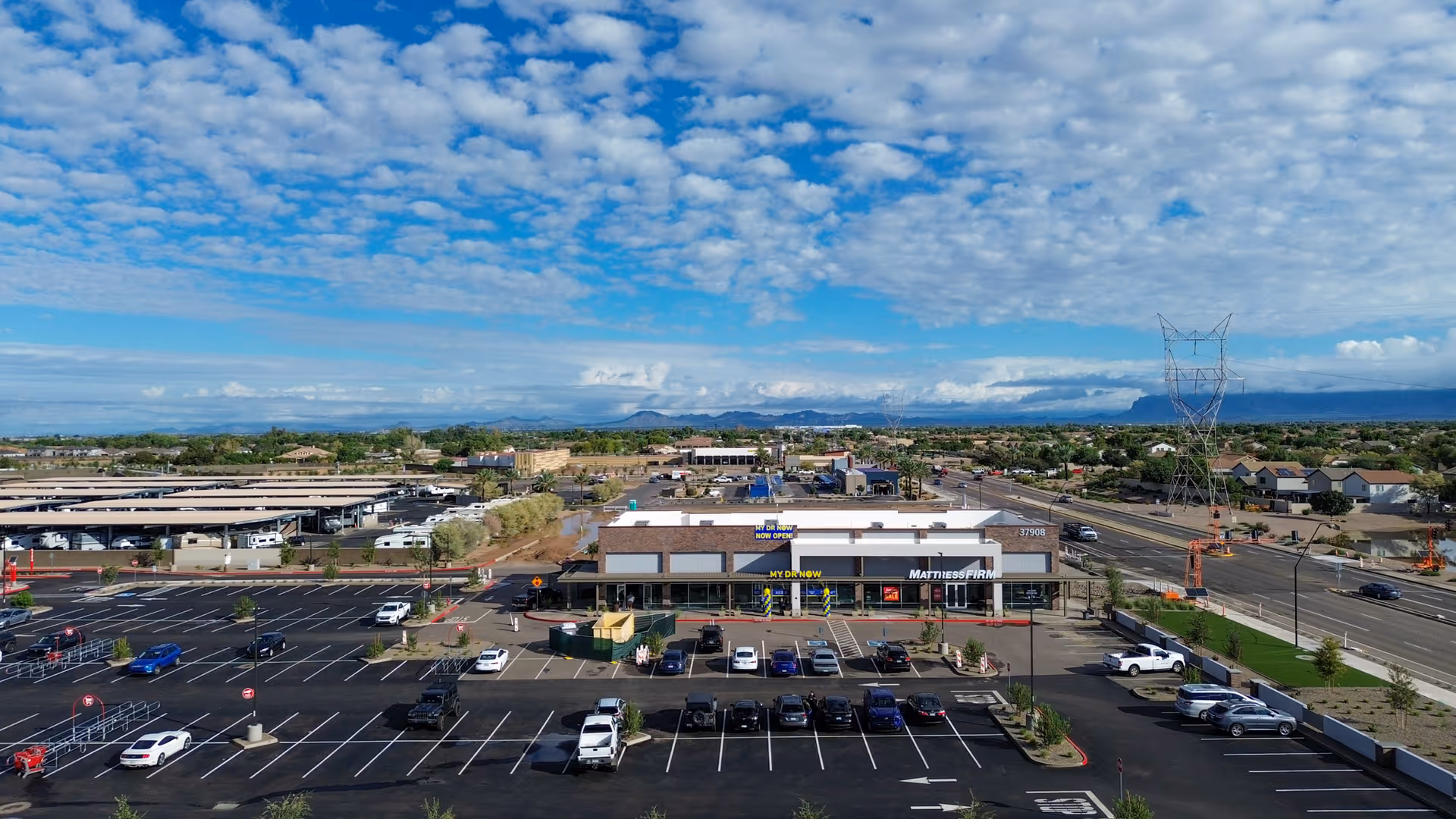 Aerial view of a shopping center with MY DR NOW storefront and a large parking lot.