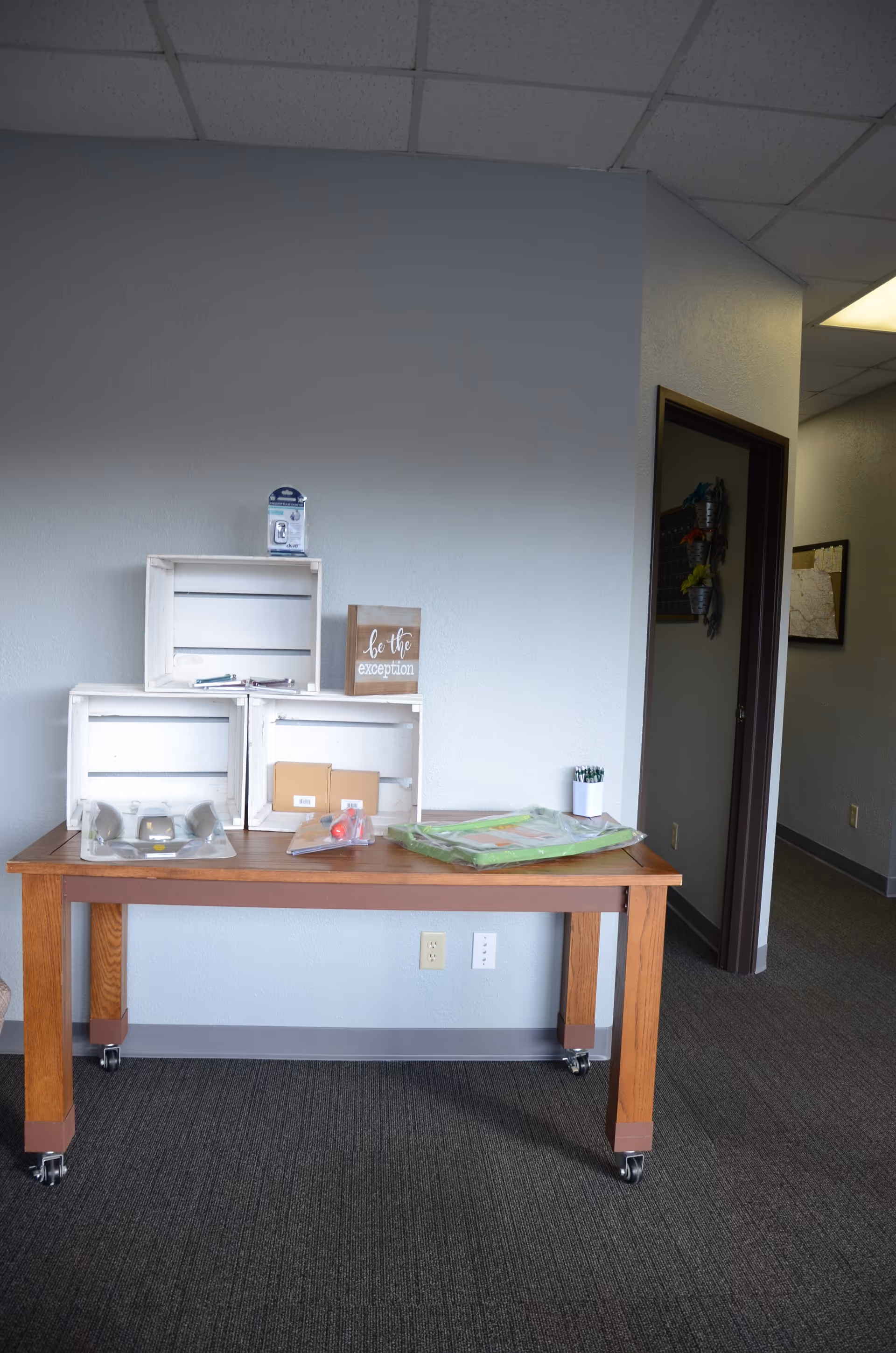 Wooden table with crates and assorted supplies in a plain, empty interior room.