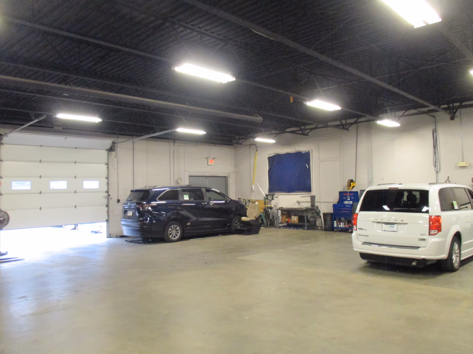 Interior service bay with two parked vehicles and workshop equipment