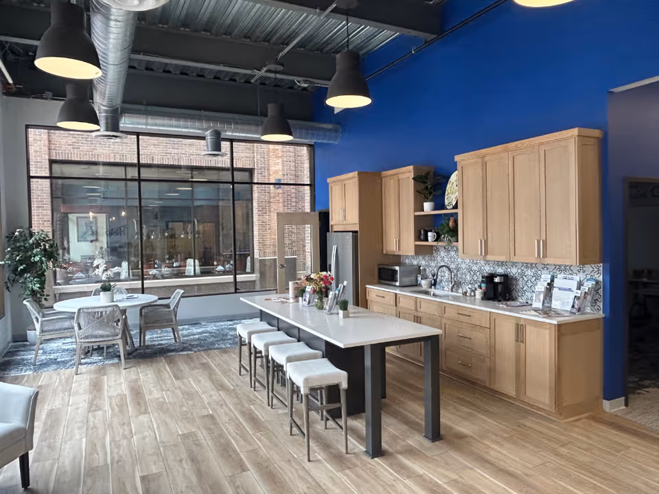 Open-concept kitchen and dining area with wooden cabinets, island, stools, and large window.