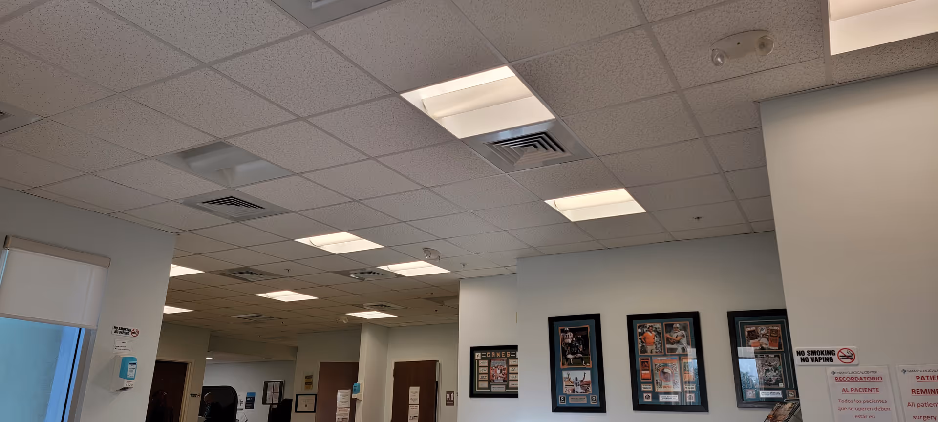 Interior space with ceiling tiles, white walls, framed wall art, and multiple signs.