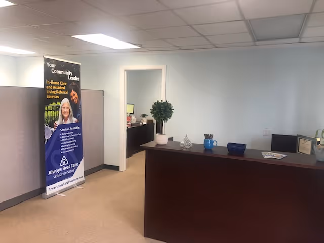 Reception area of Always Best Care facility with banner, desk, and plant.