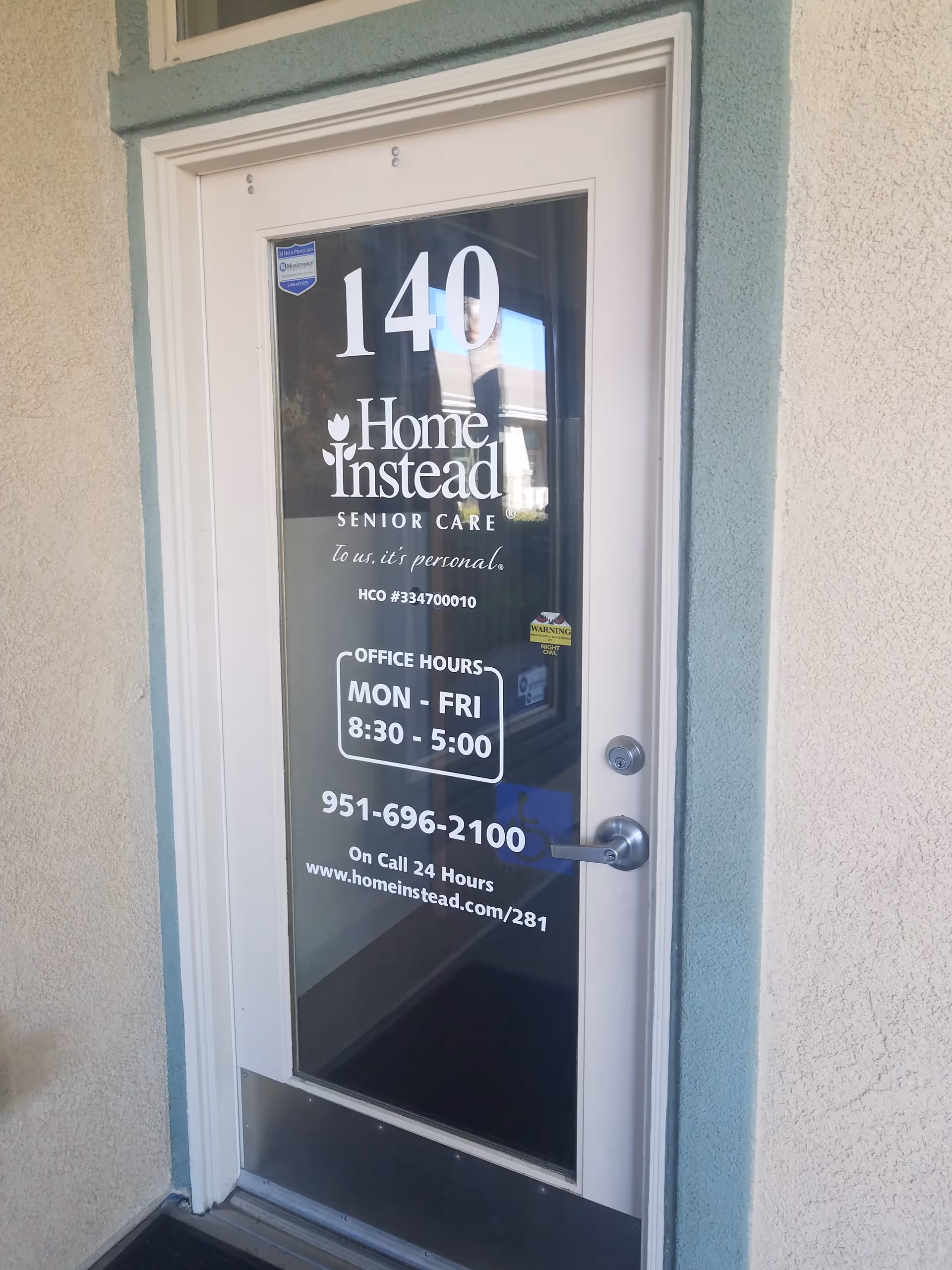 Glass door with Home Instead Senior Care signage and office hours displayed.