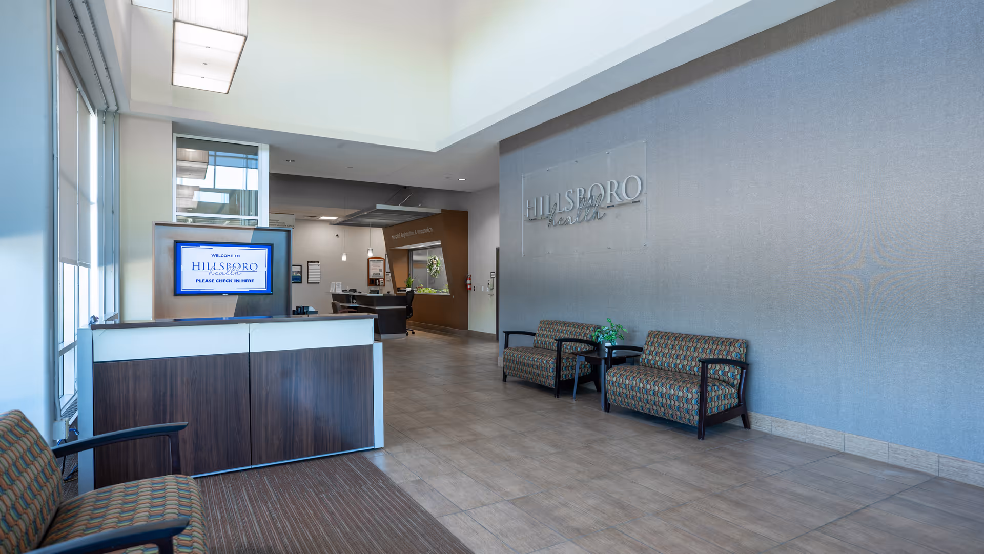 Interior Hillsboro Health lobby featuring seating area, a reception desk, and signage.