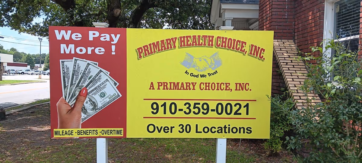 Bright double sided sign advertising Primary Health Choice with contact number in front of brick building.