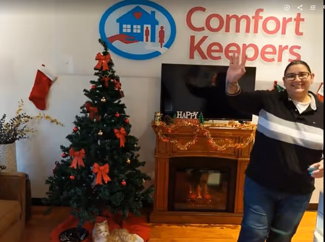 Interior living room at Comfort Keepers senior facility with Christmas tree and waving staff.
