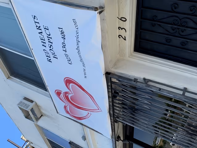 Outside building entrance with a banner reading Red Hearts Hospice and a heart logo.