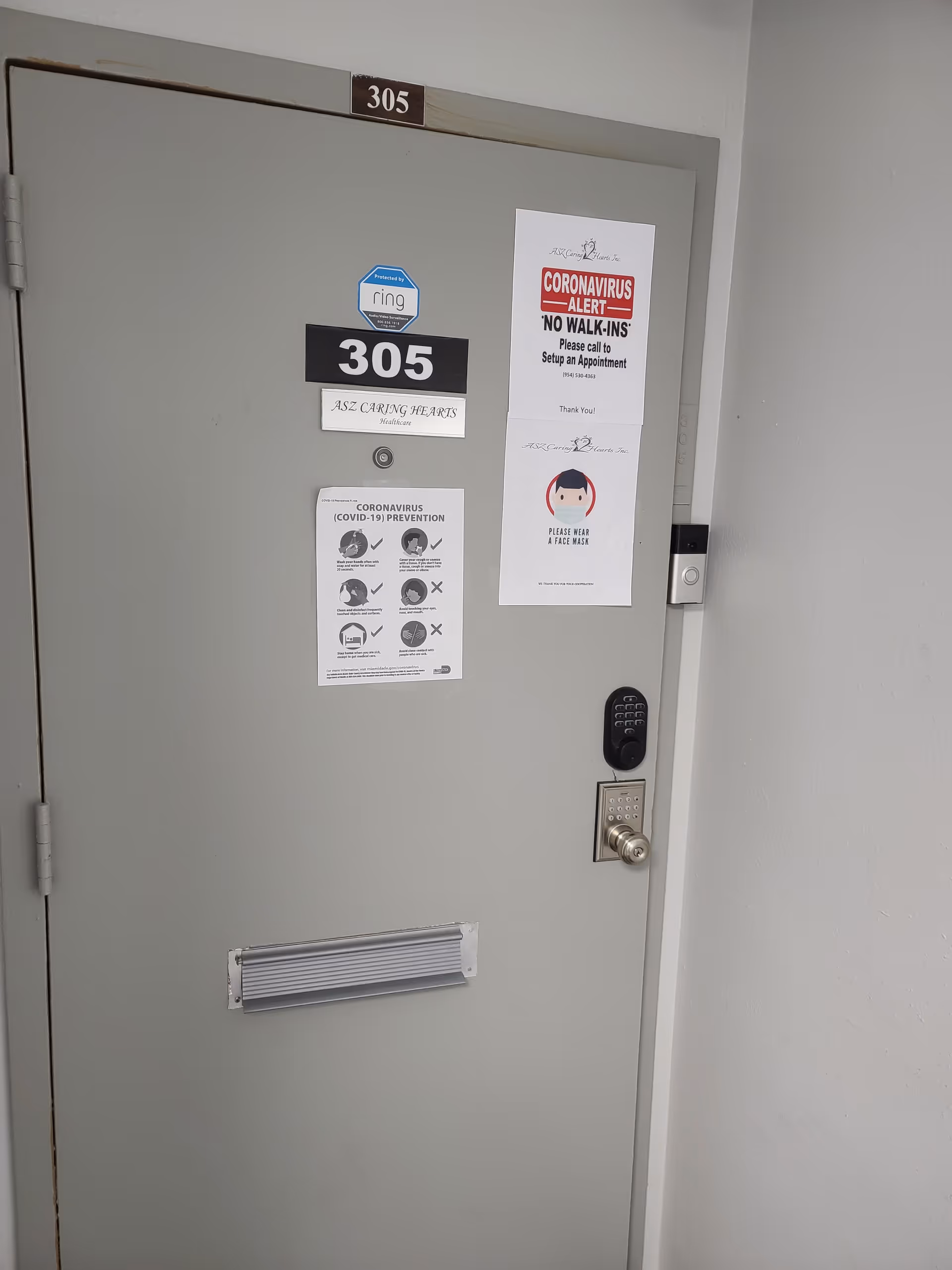 Interior door labeled 305 with COVID-19 notices, mail slot, and keypad lock.