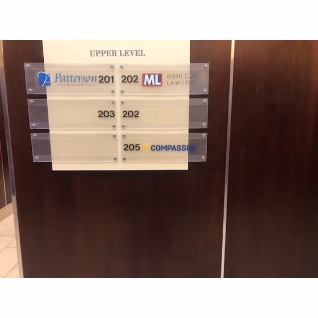 Interior wall sign listing upper level and room numbers with Compassus branding.